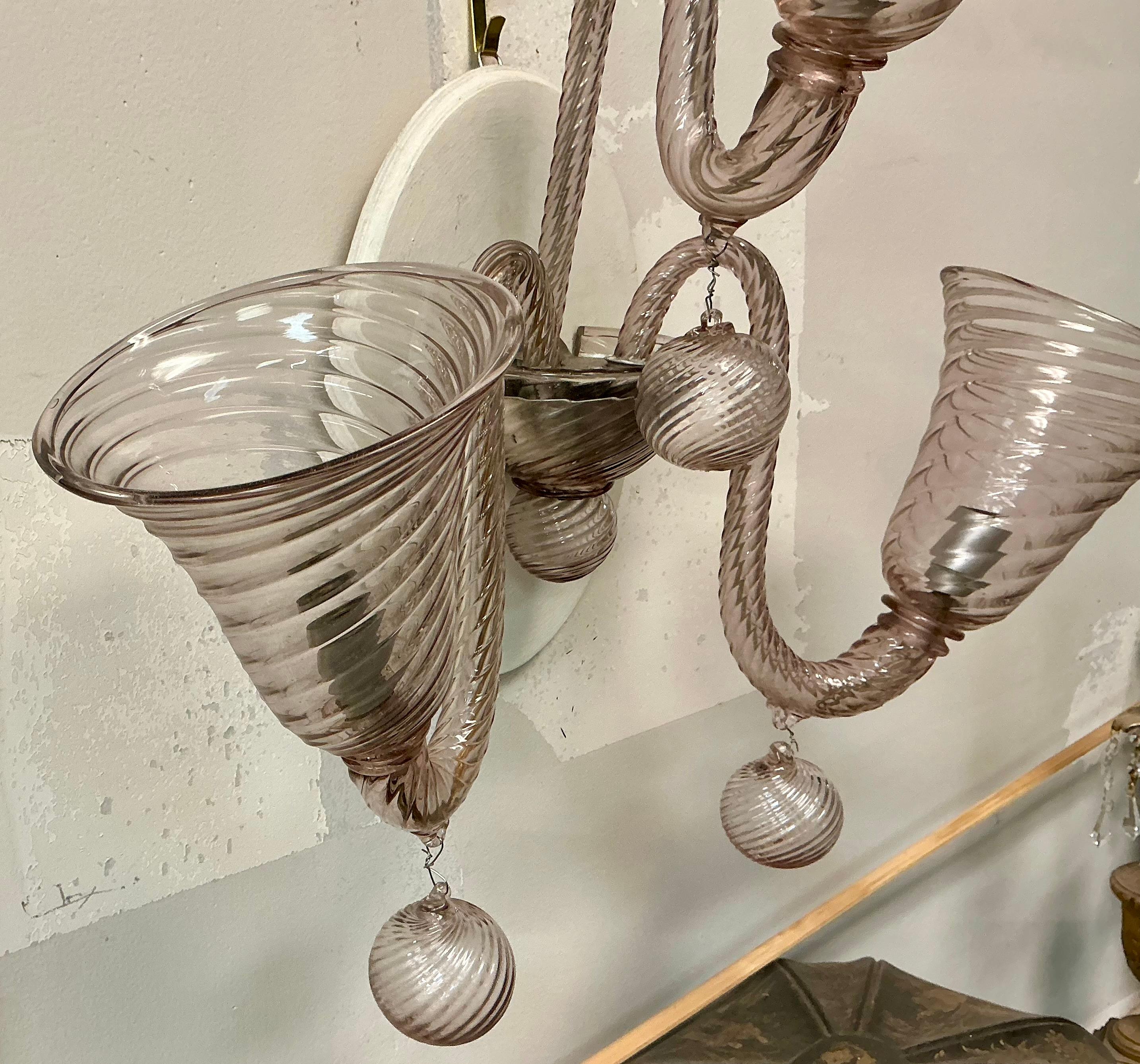 Voici une magnifique paire d'appliques murales en verre de Murano soufflé à la main. La couleur du verre est presque une lavande ou un blush. Le verre soufflé à la main est tourbillonné, et  chacun a trois bras. 
Ils sont en état de marche.