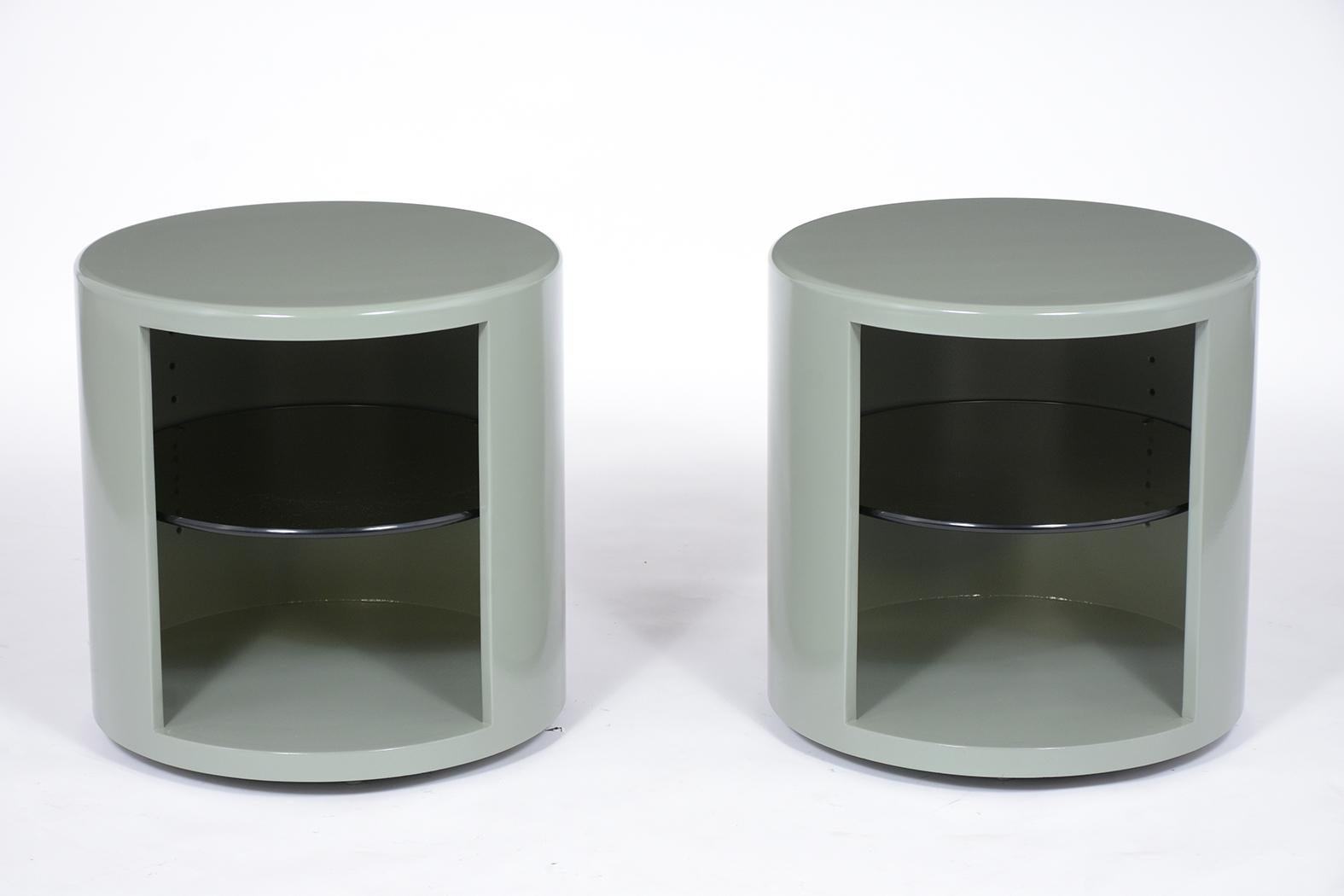 A unique pair of Mid-Century Modern round side tables handcrafted out of maple wood features a mint green color with a newly lacquered finish. The pair of end tables have an open storage space with a black tinted glass self that is adjustable. These