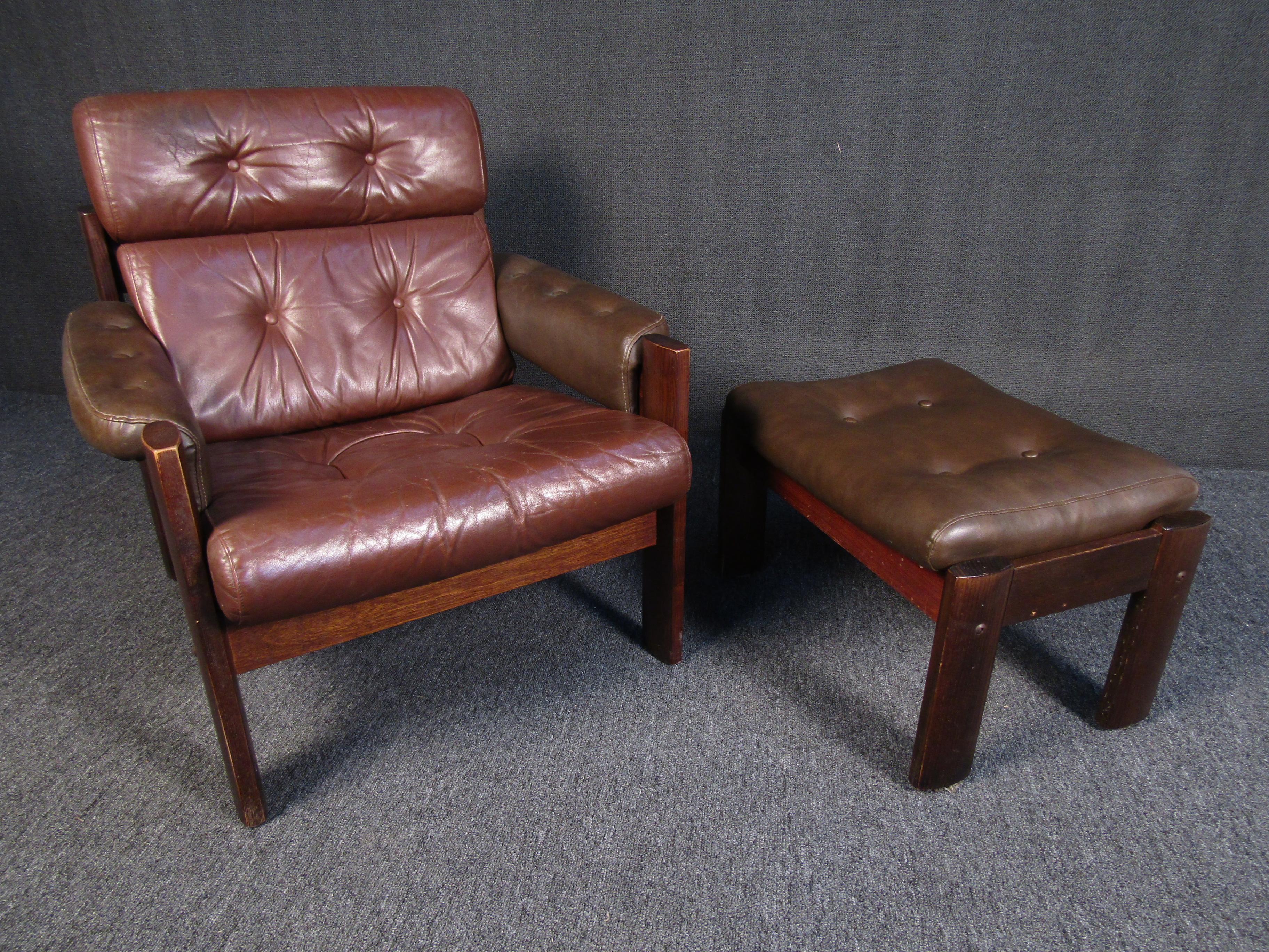 An elegant Mid-Century Modern lounge chair and ottoman that showcases two shades of leather and a rich walnut frame. Full of sophistication and character, this set is sure to be a comfortable spot for enjoying a book or relaxing. Please confirm item