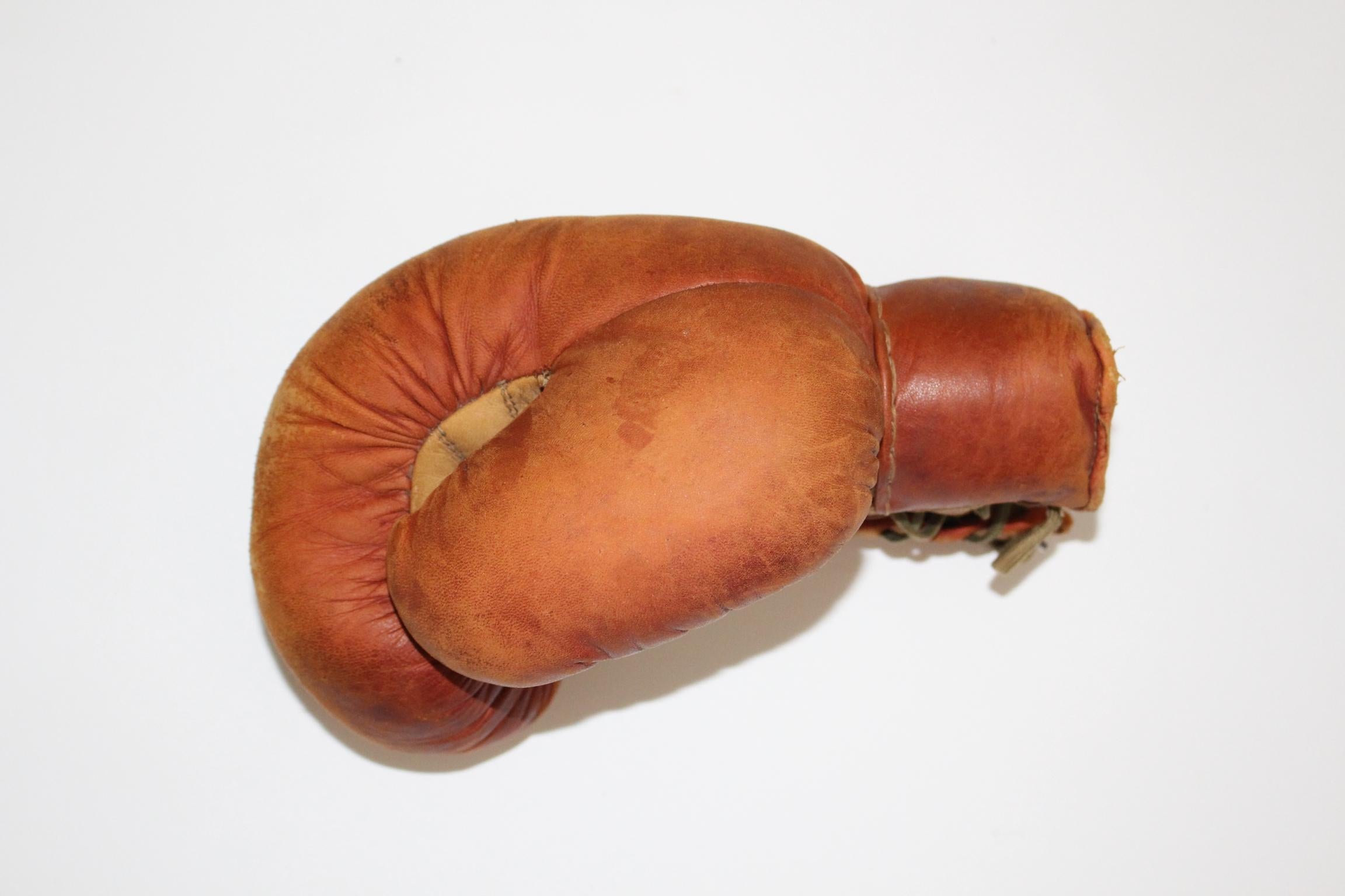 This boxing glove was made in the 1950s.
The covering of the boxing glove was made of beige and red brown leather. Also it has a lacing to fix the glove.
Good vintage condition with signs of age.

approx. measures: Length 25 cm
Depth 21 cm
Width 23