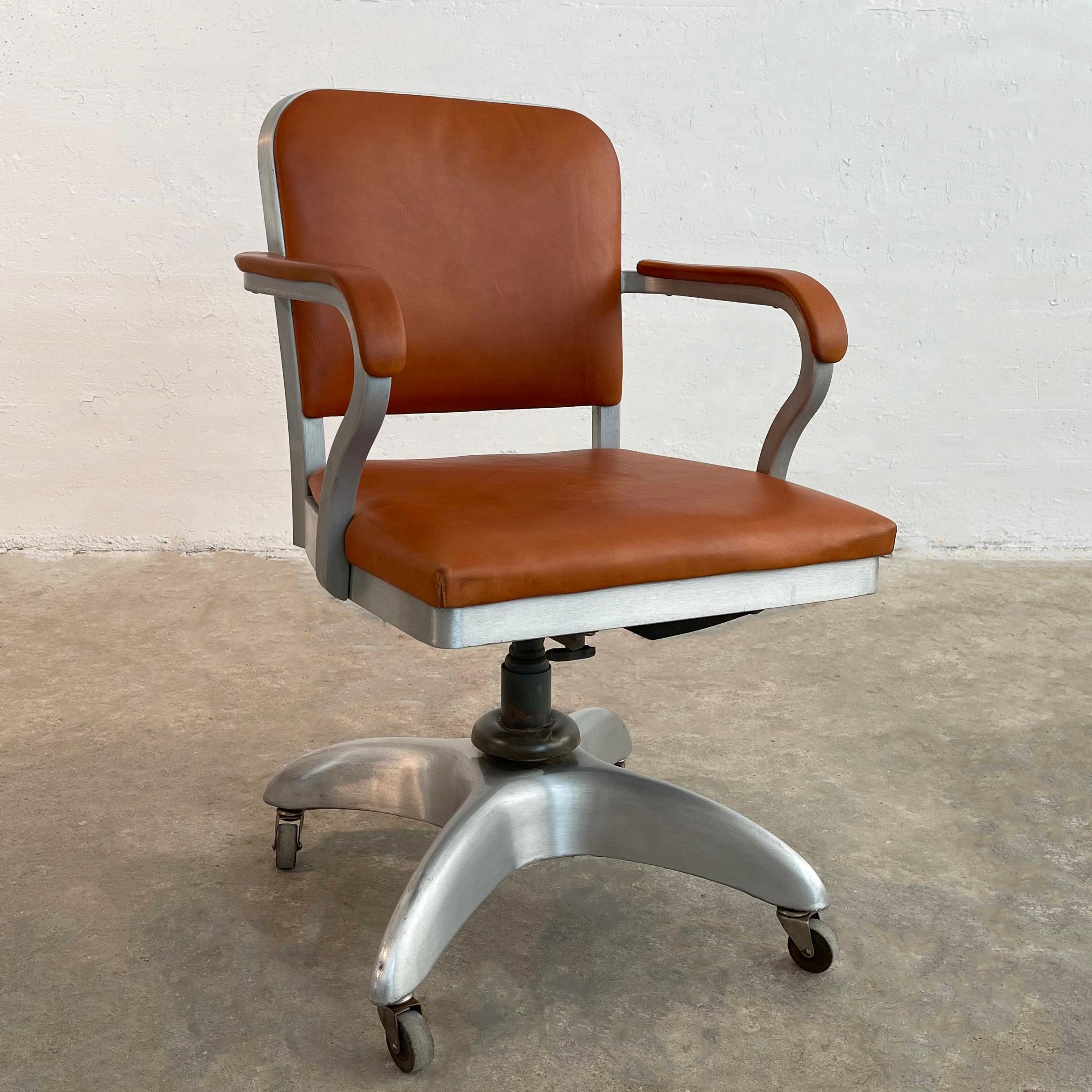Iconic, mid-century modern, machine-age, rolling, swivel desk armchair by Goodform General Fireproofing Co. features a height and tilt adjustable, brushed aluminum frame with newly upholstered seat and back in rust leather. The arm height measured