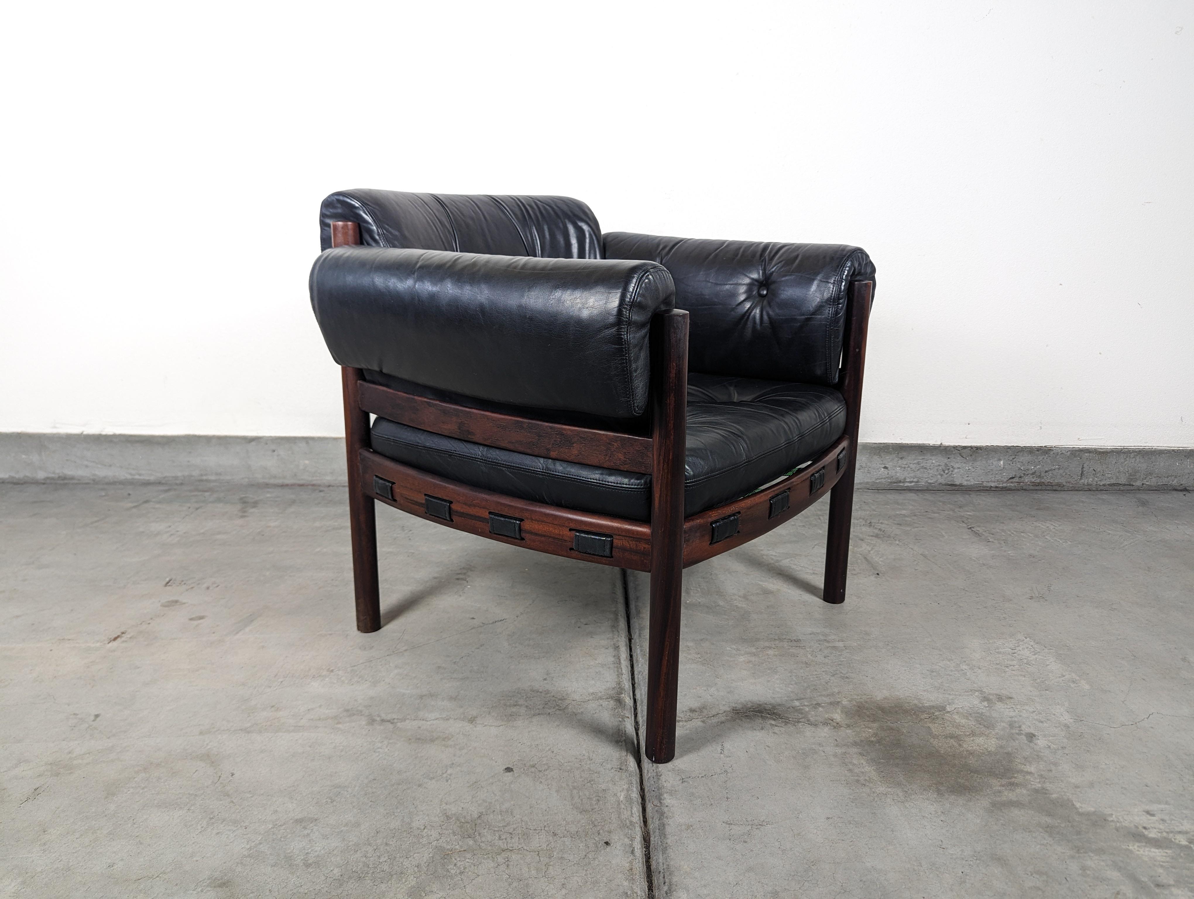 Presenting for sale, an iconic, rare, and highly sought-after mid-century modern armchair designed by the legendary Swedish designer, Arne Norell.

This particular version is fashioned from luxurious rosewood, a variant that is considerably rarer,