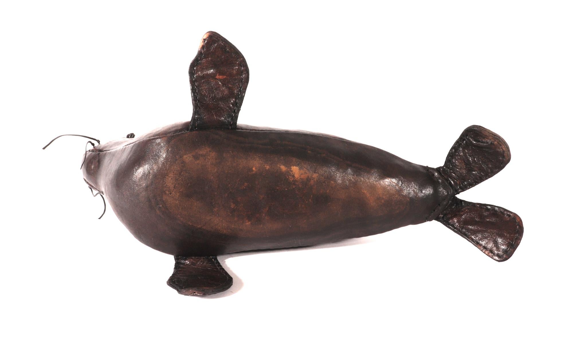 Moderne mi-centenaire  Petit modèle de sceau en cuir,
Années 1960-70

Le modèle en cuir marron d'un phoque représente le phoque la tête en l'air avec ses moustaches de chaque côté et les yeux formés par un nœud en cuir.  Le phoque a ses nageoires de