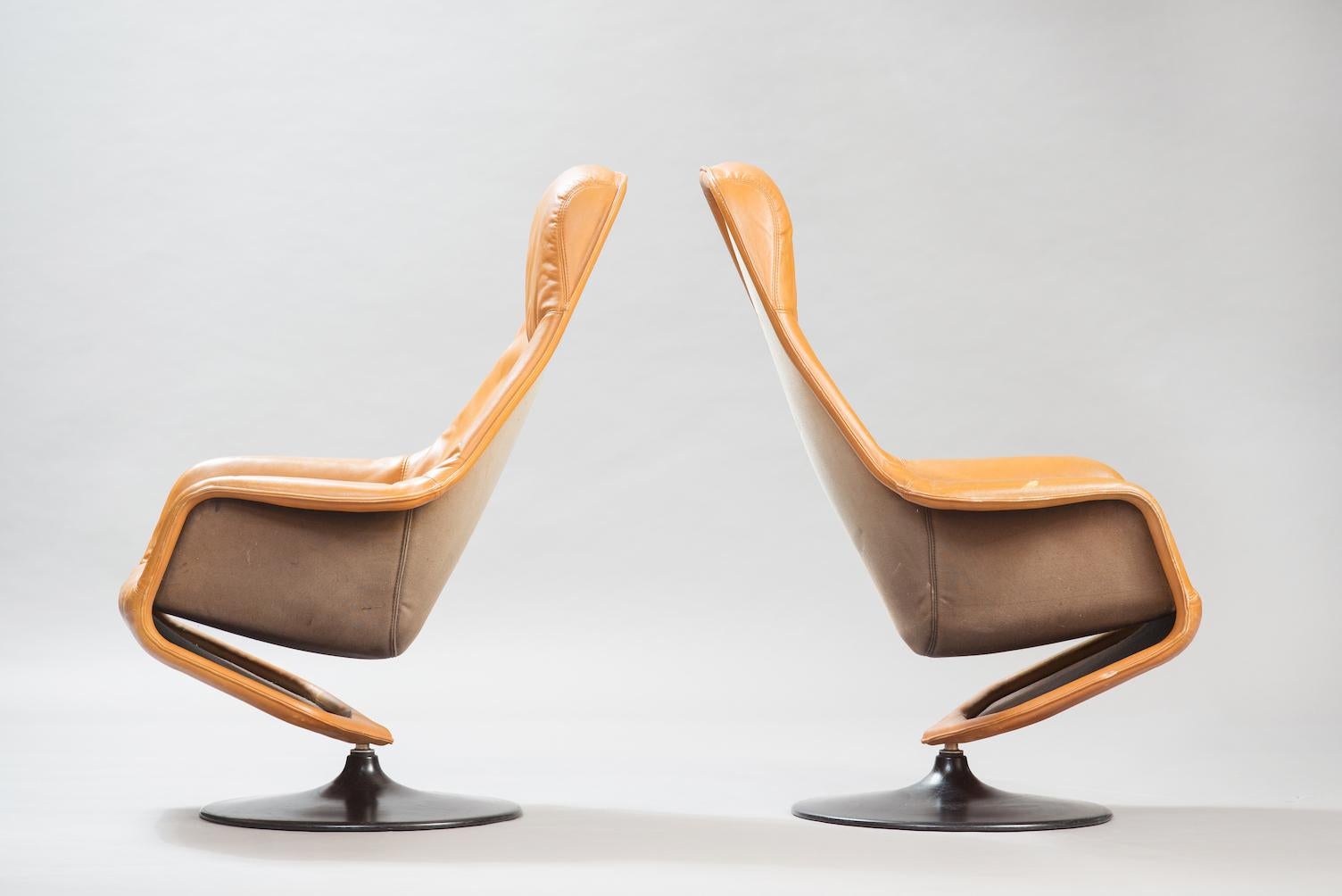 One pair of swivel lounge chairs upholstered in cognac leather in a black lacquered round base.