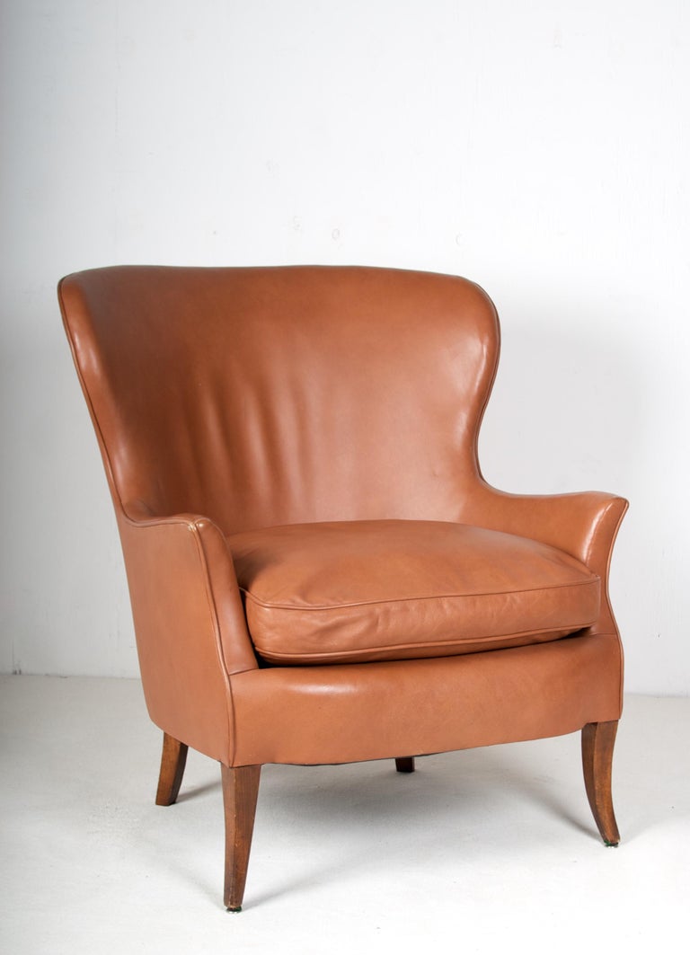 A very comfortable early mid century wingback lounge chair,
Upholstered in fine cognac colored leather. The loose seat
Cushion has feather fill. The leather is in almost perfect 
Condition, there is some slight darkening of color on the
Edge of