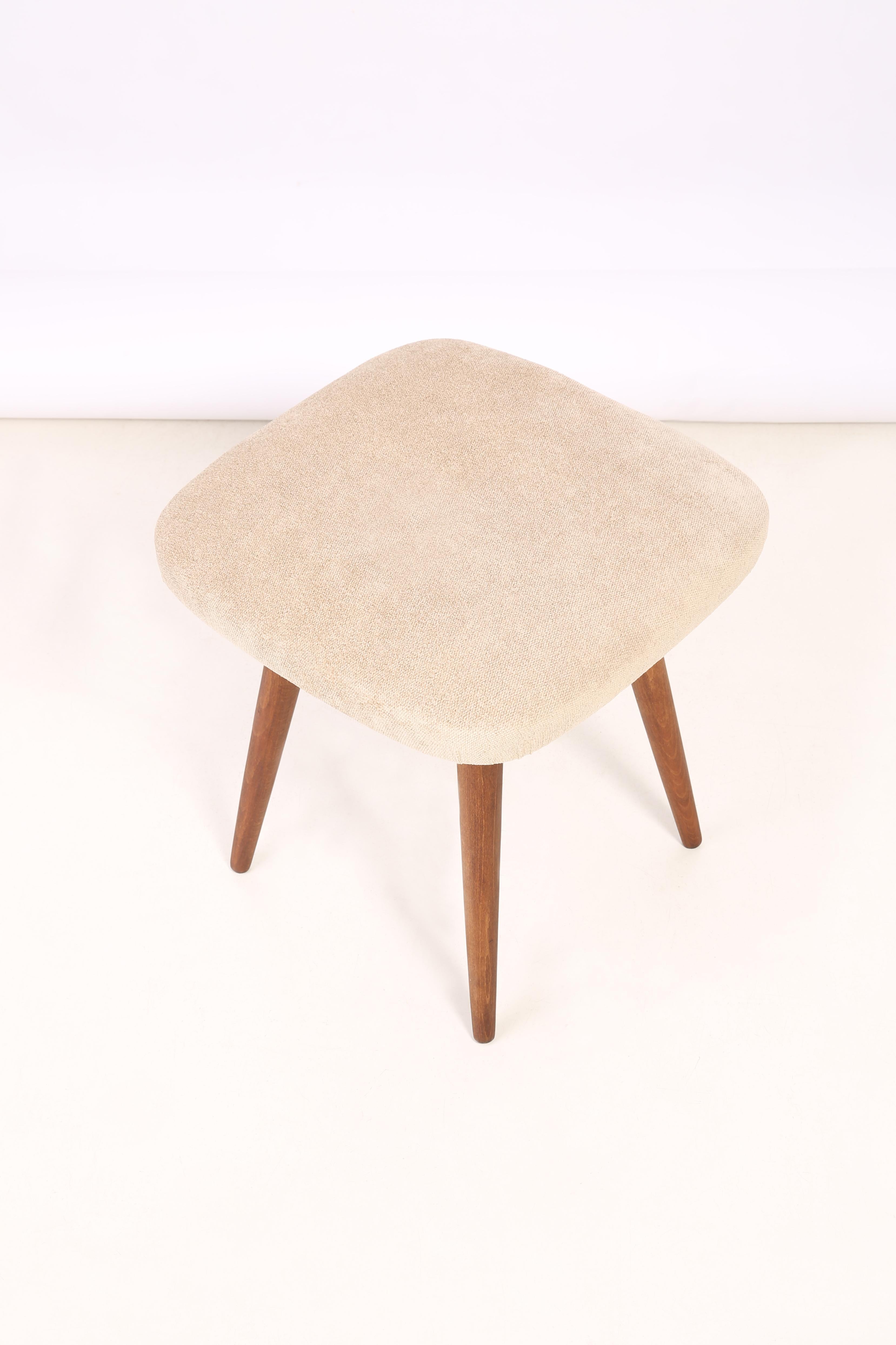 Stool from the turn of the 1960s and 1970s. Beautiful, well crafted beige upholstery. The stool consists of an upholstered part, a seat and wooden legs narrowing downwards, characteristic of the 1960s style. We can prepare this stool also in another