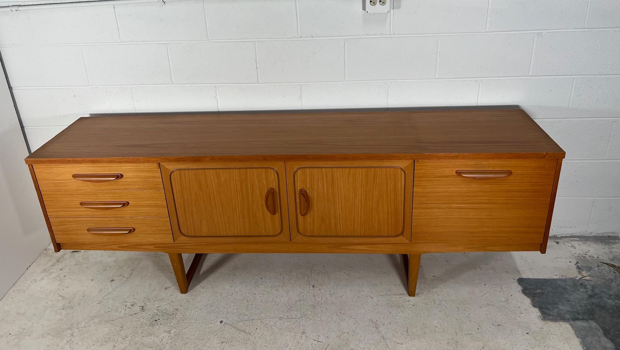 Light wood credenza by Stateroom. Made in England.

Featuring sculpted handles and a drop down door bar cabinet. Very good condition overall. Chip on one drawer handles. Some marks and light scratches as shown in photos. Chip on right corner. Some