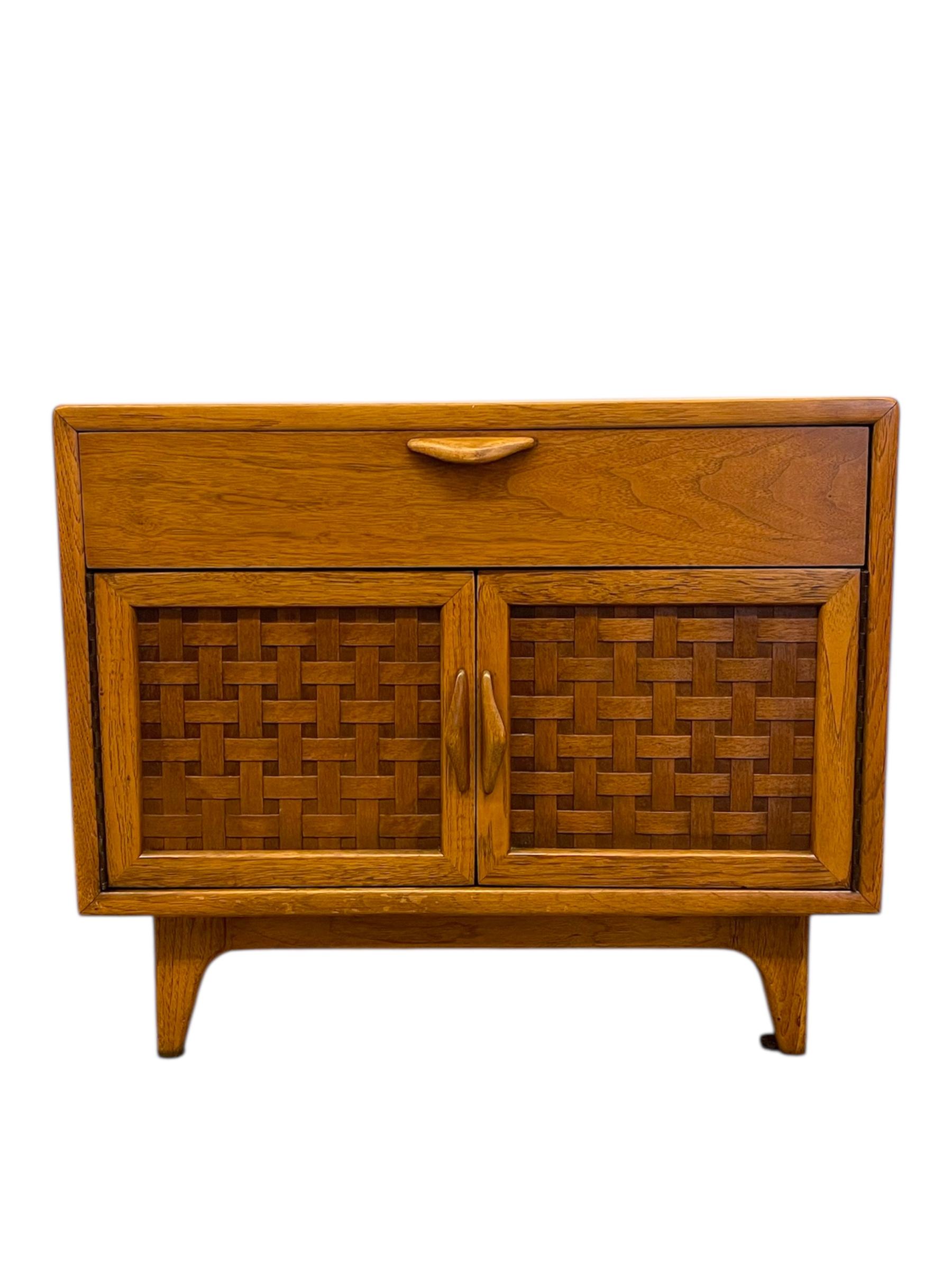 This vintage mid-century modern cabinet by Lane Furniture, produced in Altavista, Virginia in the 1970s, showcases the brand's signature craftsmanship and distinctive design detailing. Constructed from likely oak with matching veneer panels, the