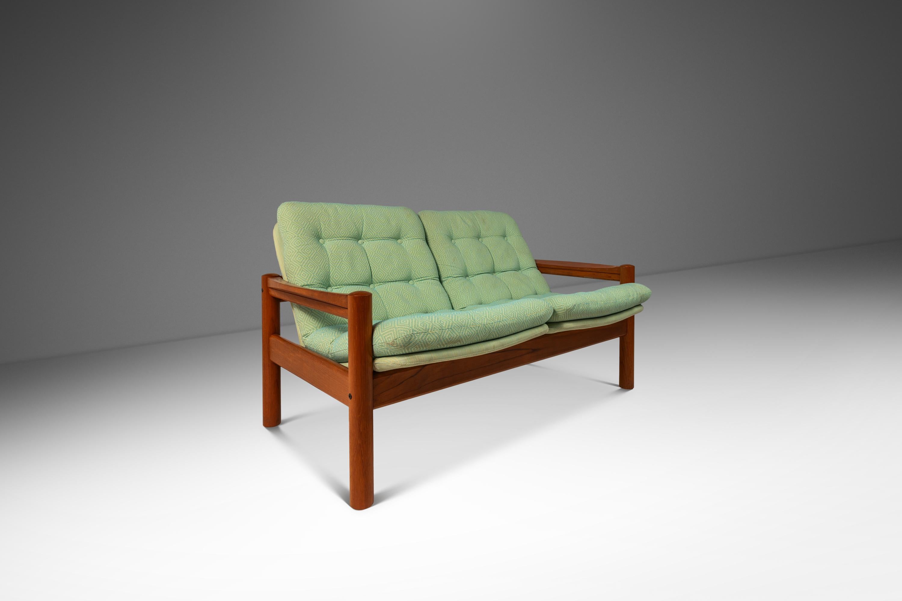Introducing a complete set of two Danish-made high-back lounge chairs with accompanying foot stools, two seater loveseat and matching side table. Crafted in the mid-1970's by the lauded Domino Møbler this expansive set is crafted from solid slabs of