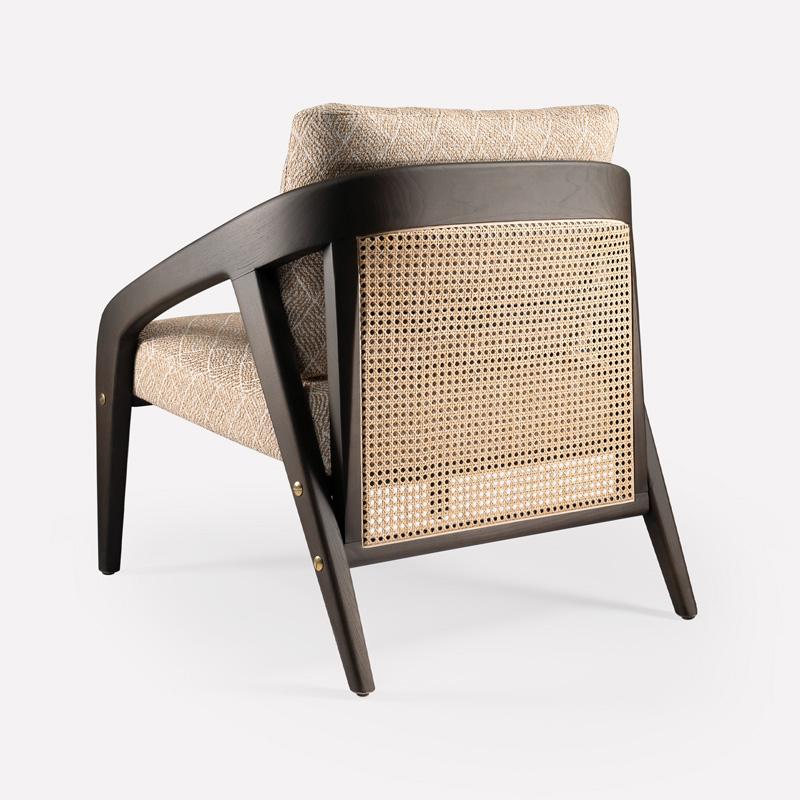 Questa poltrona lounge incarna una raffinata estetica moderna di metà secolo, fondendo una scultorea lavorazione del legno con un'imbottitura ricca e tattile. La struttura è caratterizzata da braccioli elegantemente curvati in legno di noce che si