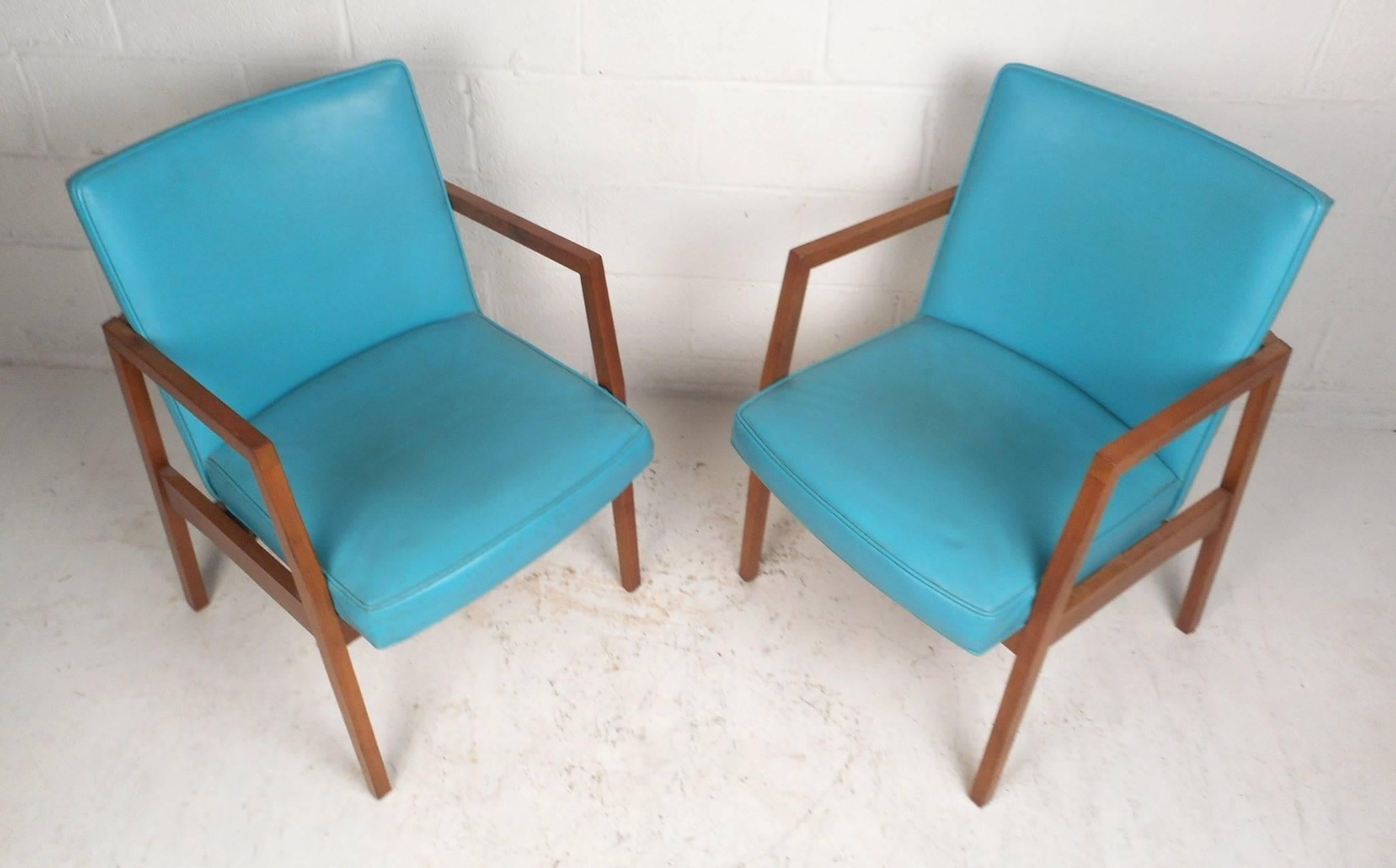 This beautiful pair of vintage modern armchairs feature a walnut frame with angled back legs and elaborate blue vinyl seats. Sleek and comfortable design with high sculpted arm rests and thick padded seating. This fabulous pair makes the perfect