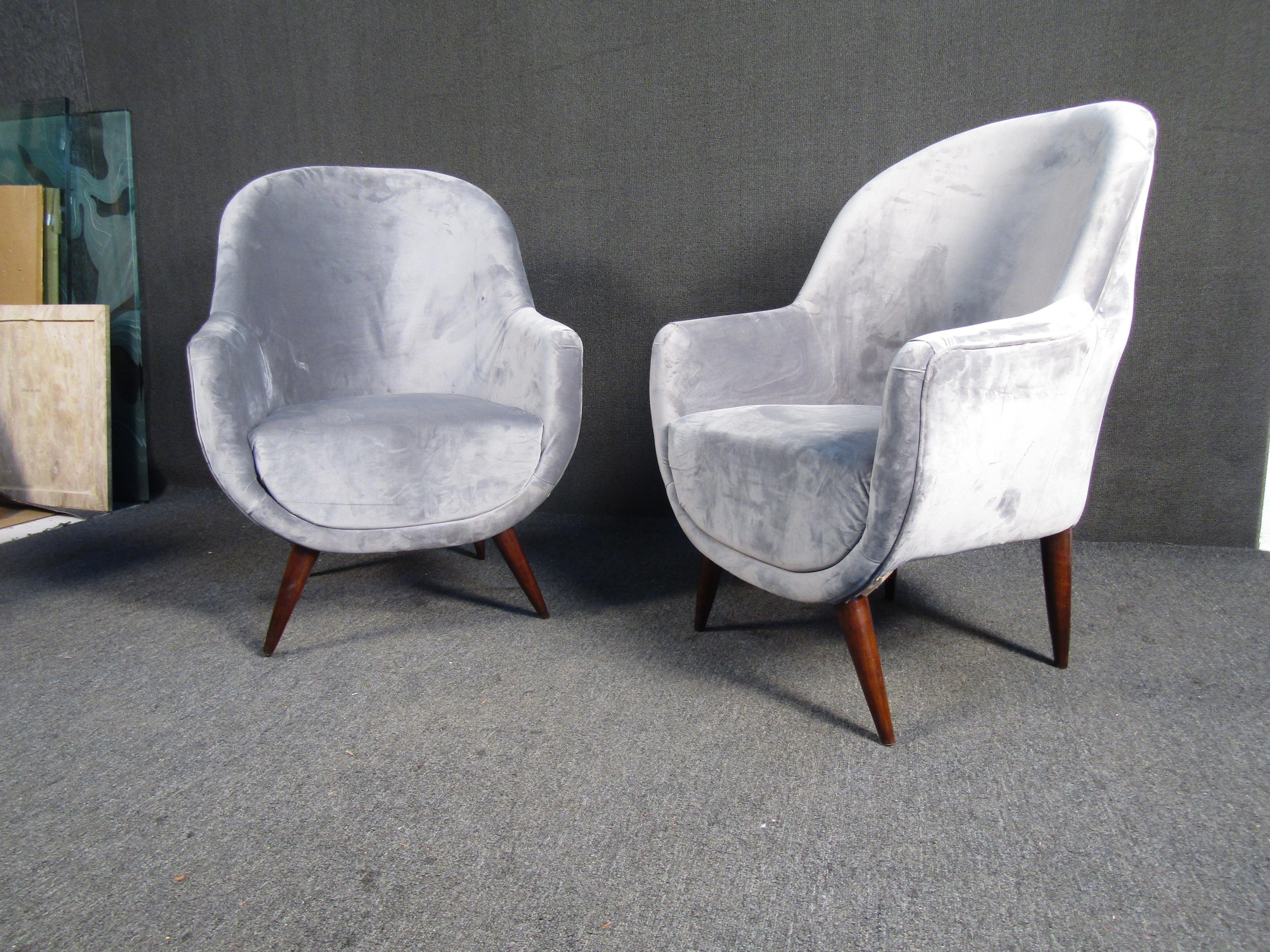 Unique vintage modern lounge chairs. These plush lounge chairs are upholstered in a comfy fabric with tapered wooden legs. The uniquely shaped chairs are sure to be a conversation starter. Perfect chairs for entertaining!

Please confirm item