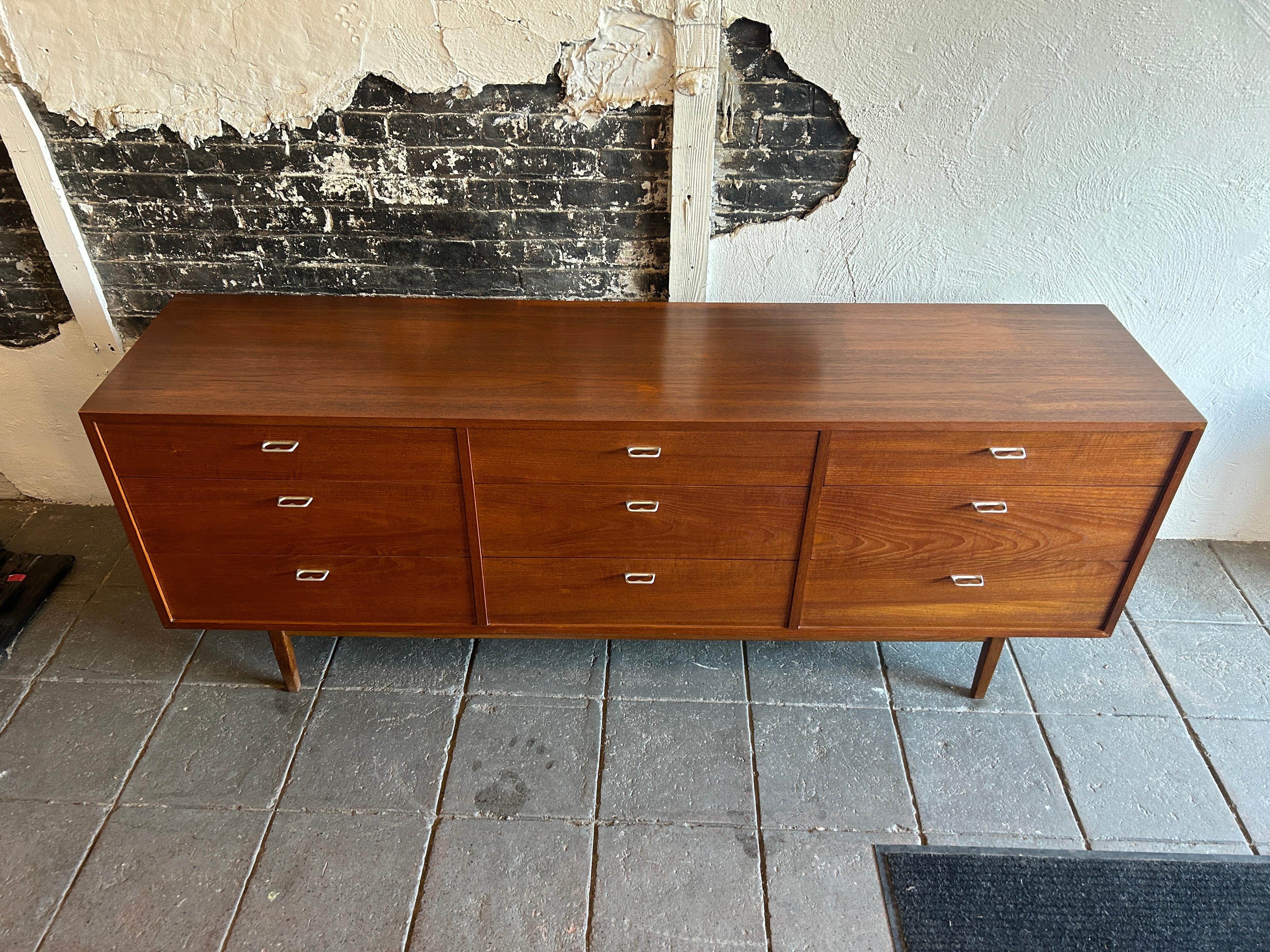 American Mid-Century Modern low 9 drawer walnut dresser with aluminum two finger pulls. Really Good Design and clean inside and out in good vintage condition. Walnut veneer dressers with solid wood drawers and dovetail joints. All drawers are clean