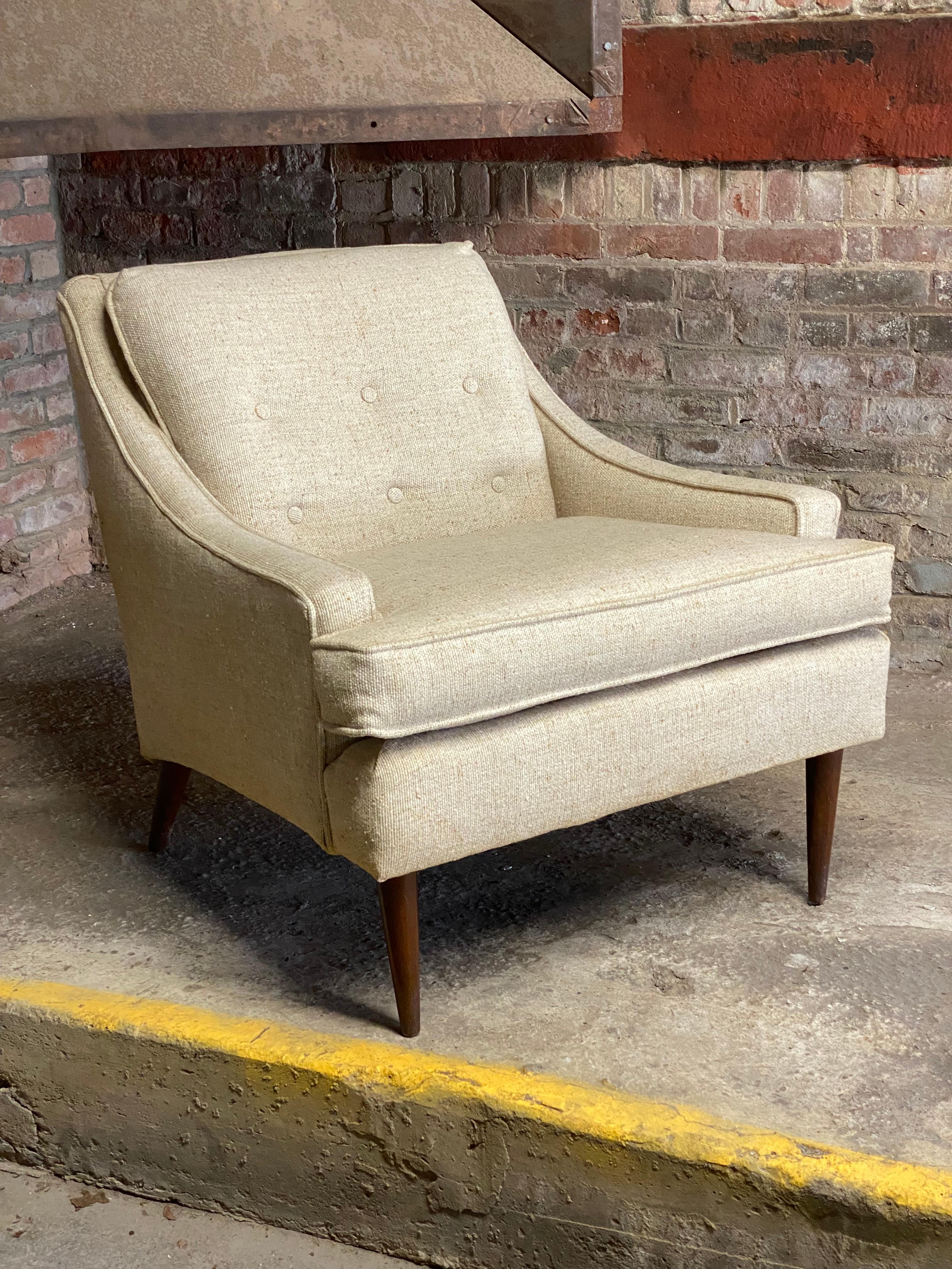 A fine Mid-Century Modern low slung arm chair with tapered and flared wood legs. Six button back with a loose cushion seat. Circa 1960-70. A good quality chair with very nice lines. The chair was reupholstered in the late 1980s in a heavy duty