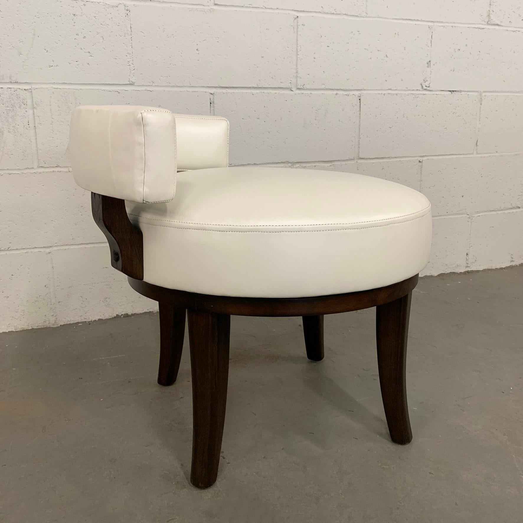 Mid-Century Modern, swivel, vanity chair features a low profile, curved backrest, upholstered in cream leather with lacquered black, mahogany frame. The seat width is 20 inches.