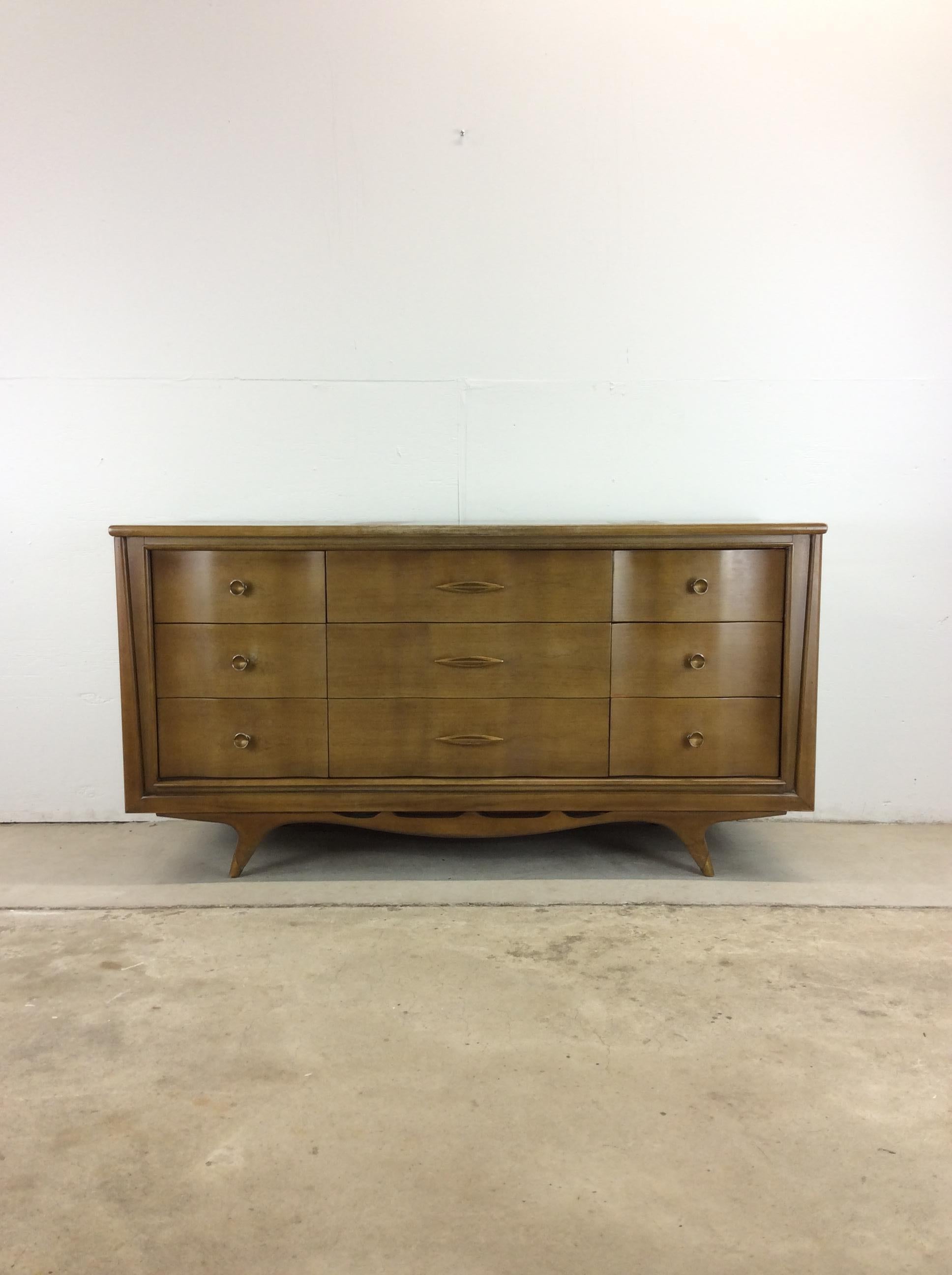This mid century modern lowboy dresser “The Appleton” by Kent Coffey features hardwood construction, beautiful walnut veneer with original finish, nine dovetailed drawers with brass accented hardware, and brass capped tapered legs.  Matching highboy