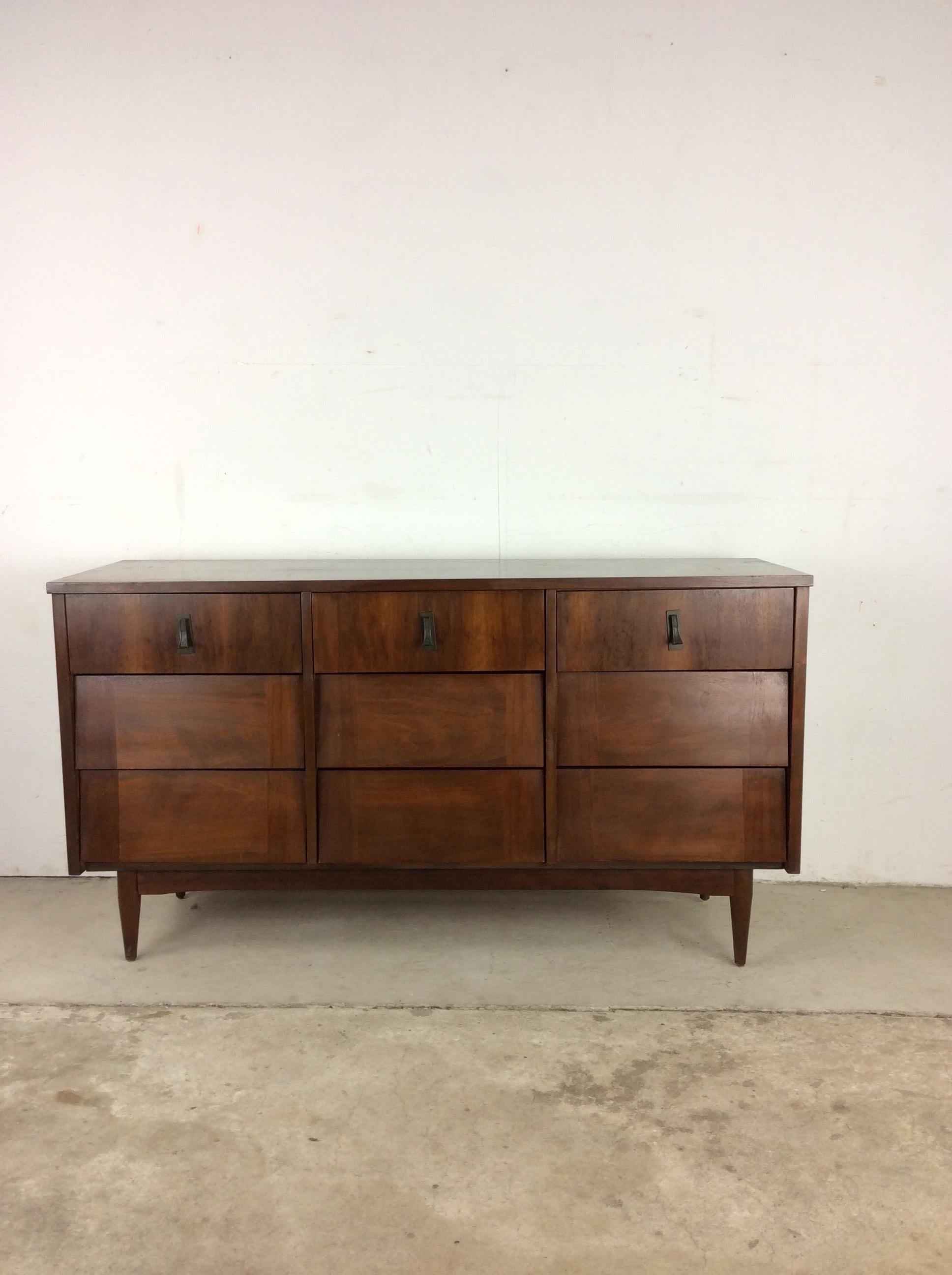 This Mid-Century Modern lowboy dresser features hardwood construction, original walnut finish, nine dovetailed drawers with louvered style drawer fronts, brass accented hardware, and tapered legs.
?Dimensions: 55.75w 17.75d 30.5h?


.