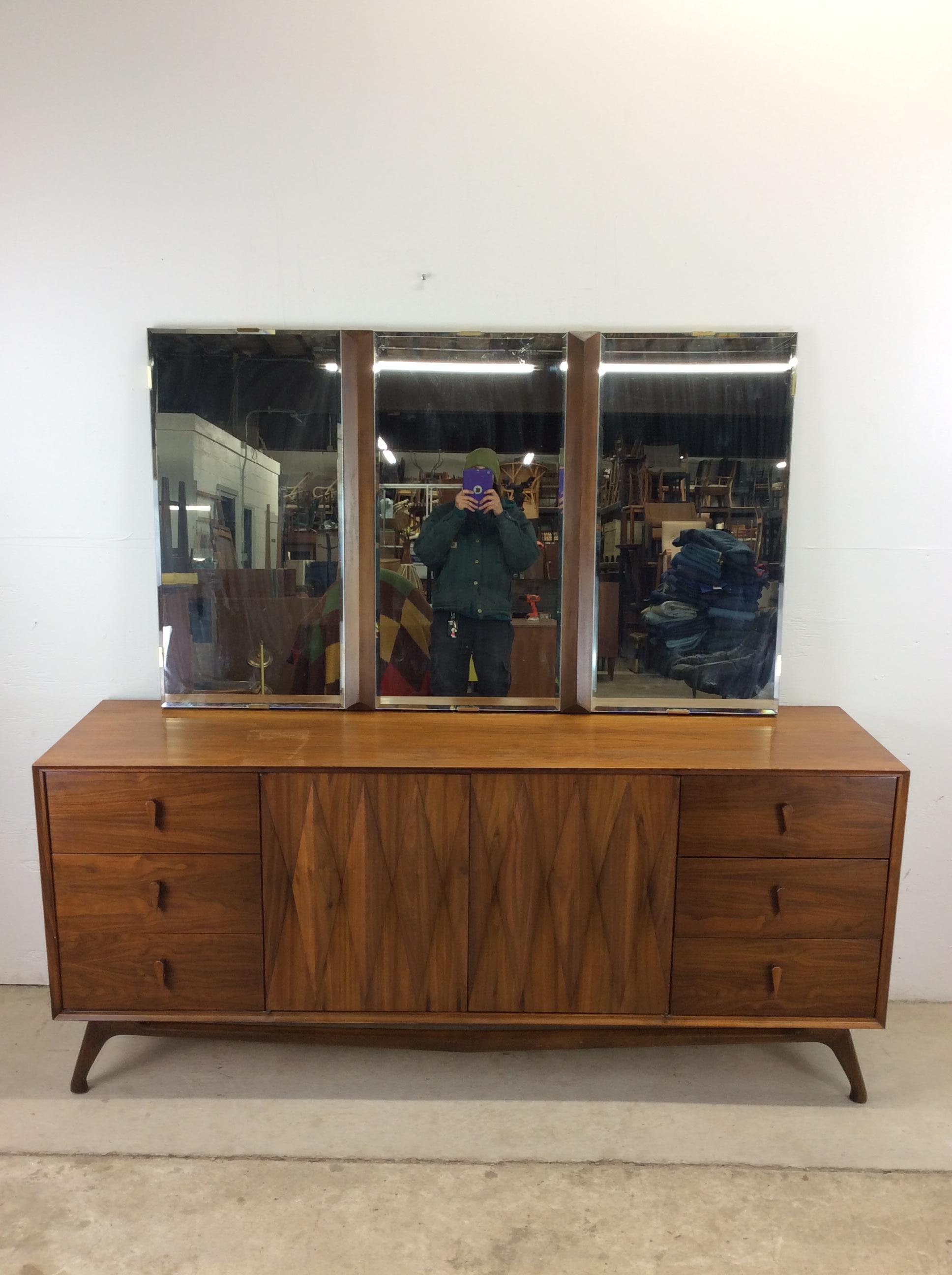 This mid century modern lowboy dresser by Albert Parvin for American of Martinsville features hardwood construction, walnut veneer with original finish, nine dovetailed drawers, unique wood drawer pulls, beveled diamond pattern cabinet doors, and