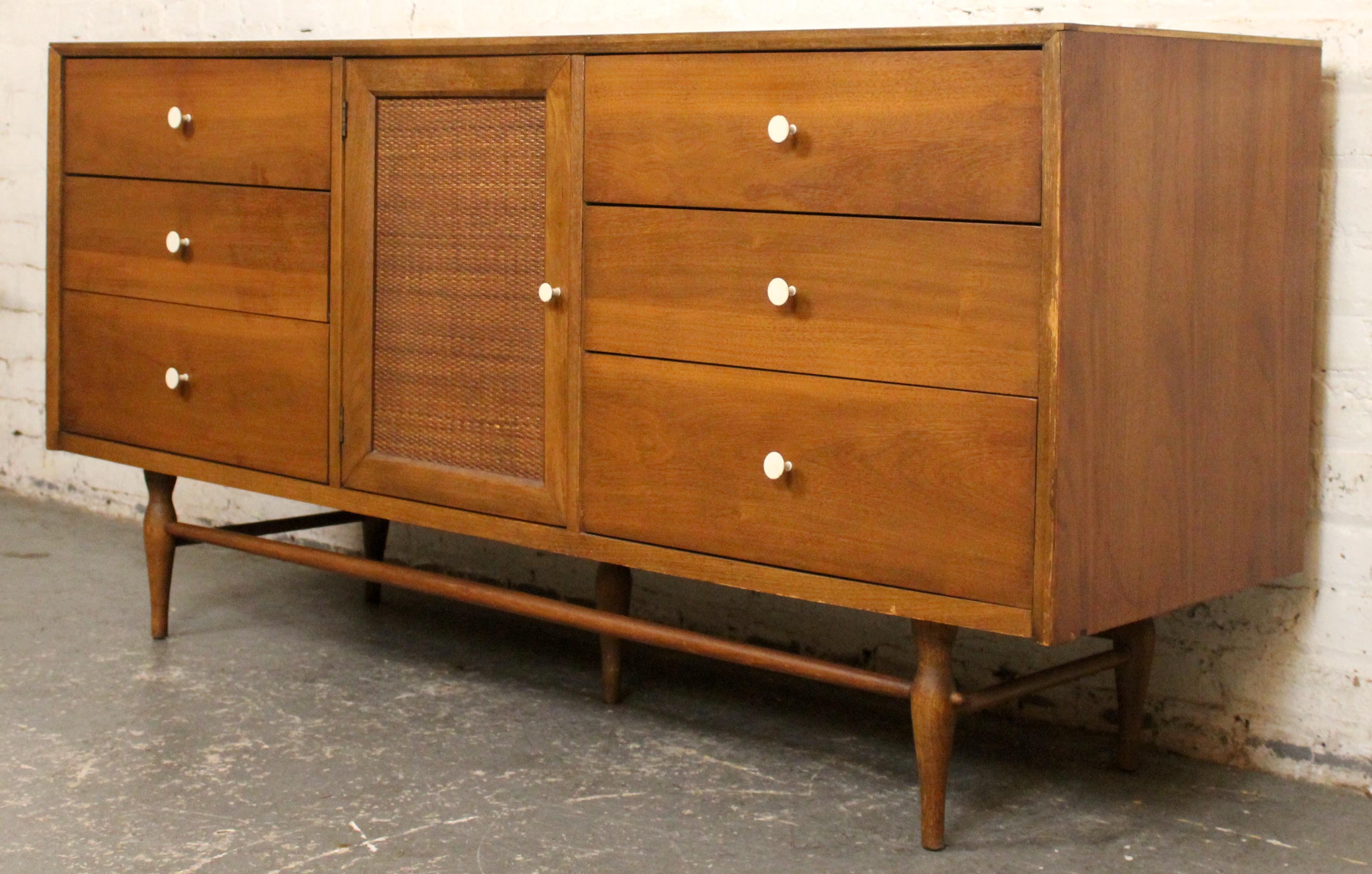 Mid-Century Modern walnut lowboy dresser by Harmony House, featuring nine drawers in total. Six wide drawers flank a central cane-front door that opens to reveal three smaller interior drawers. A handsome piece with clean lines and subtle textural