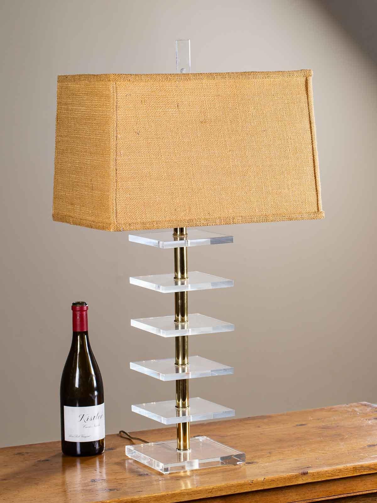 This Lucite and brass Mid-Century Modern lamp from France, circa 1965 has a unique arrangement of six square blocks of Lucite separated by brass cylinders. The distance between the Lucite sheets and the gleam of the brass give an intriguing