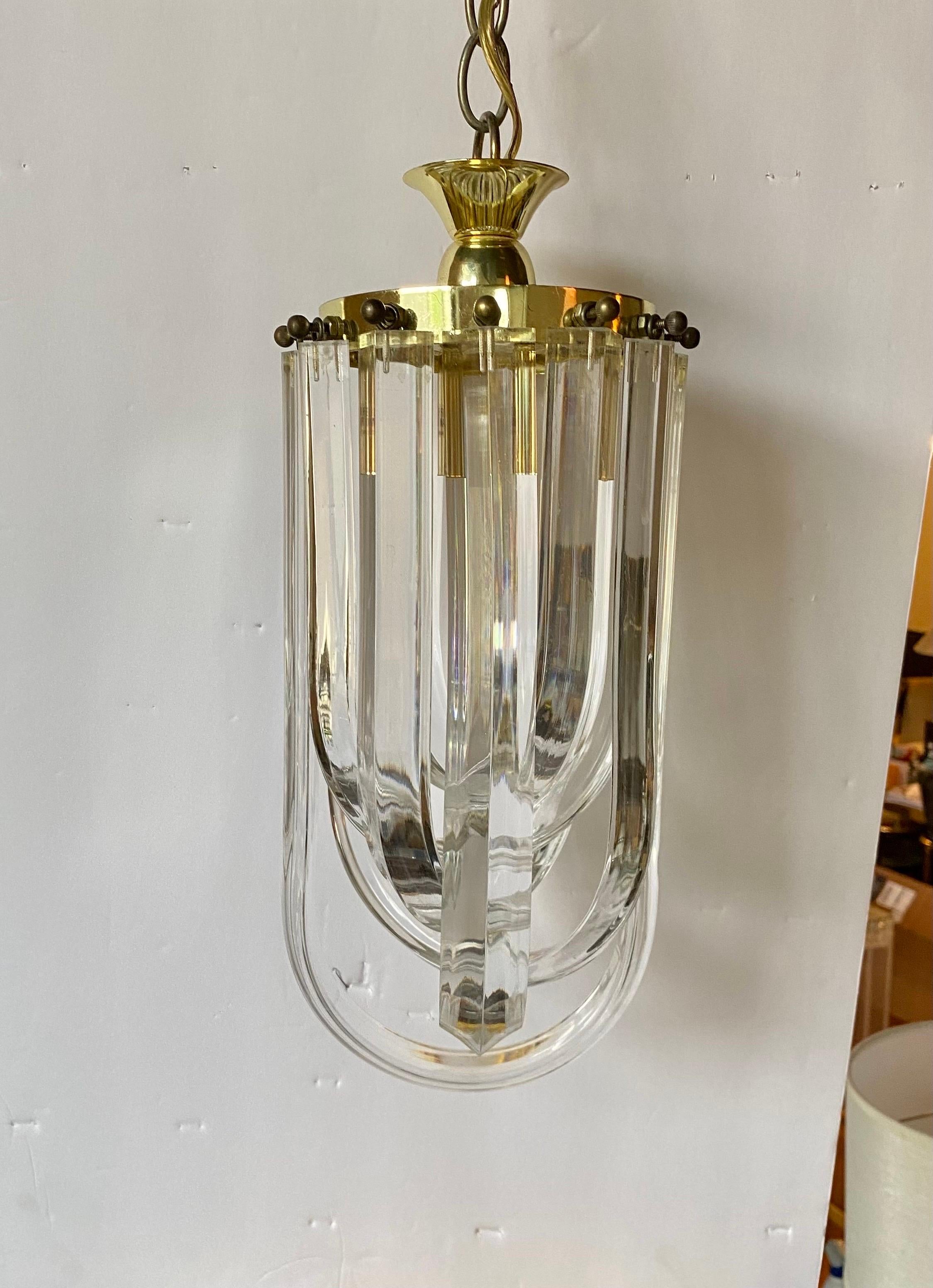 Mid-Century Modern bent Lucite ribbon chandelier pendant.  This sculptural light fixture features curved clear Lucite loops suspended from a gold brass plated frame.  Perfect size for a powder room bathroom or entry hallway. 

Chain measures 13