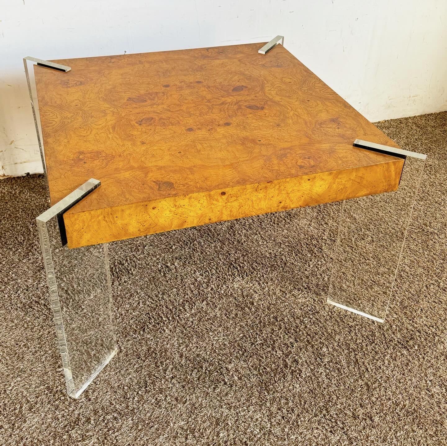 Experience the blend of vintage and contemporary with this Mid Century Modern Lucite and Burl Wood Coffee Table. This piece showcases sleek Lucite legs and a rich Burl wood top, combining mid-century elegance with modern flair. The transparent legs
