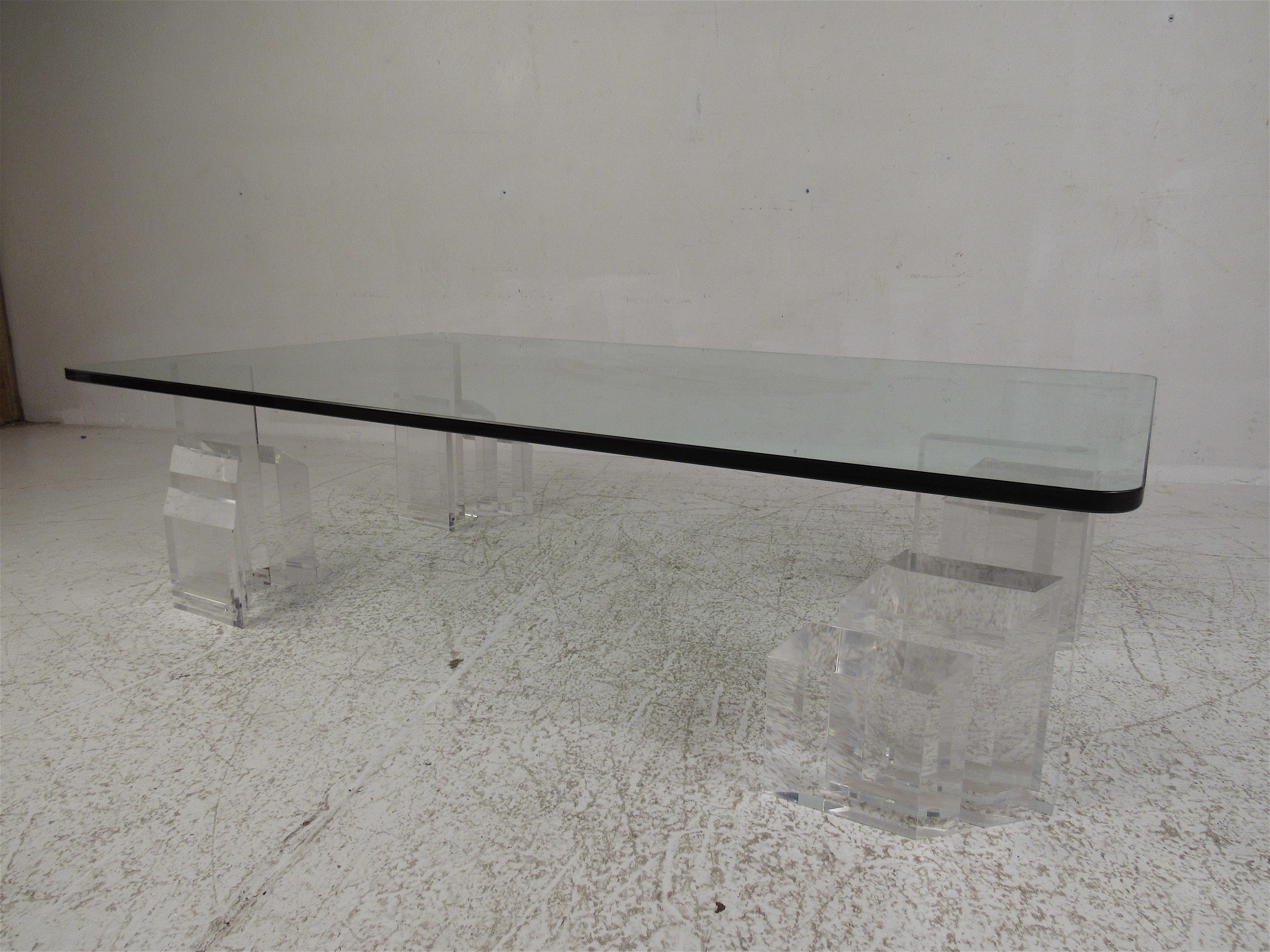 Esta impresionante mesa de centro moderna de estilo vintage tiene un gran tablero rectangular de cristal con un ligero tinte verde. Un diseño inusual con cuatro piezas individuales de Lucite. Un elegante diseño graduado con bordes biselados hace que