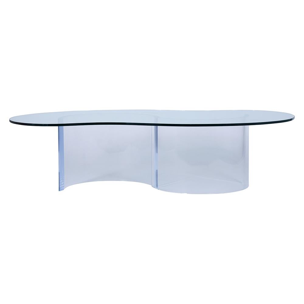 A fabulous midcentury-style cocktail table crafted from Lucite and clear glass. This coffee table features a unique two-piece waveform Lucite base topped with a kidney shape clear temper glass top with a flat polished. The beautiful table makes for