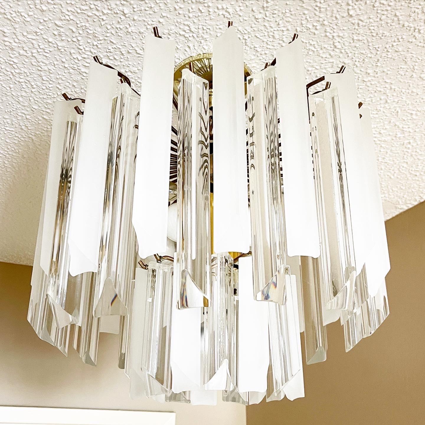 Exceptional vintage mid century modern 2-tier lucite chandelier. Features a gold cage which holds the frosted and clear lucite polygons. Holds 11 bulbs.
