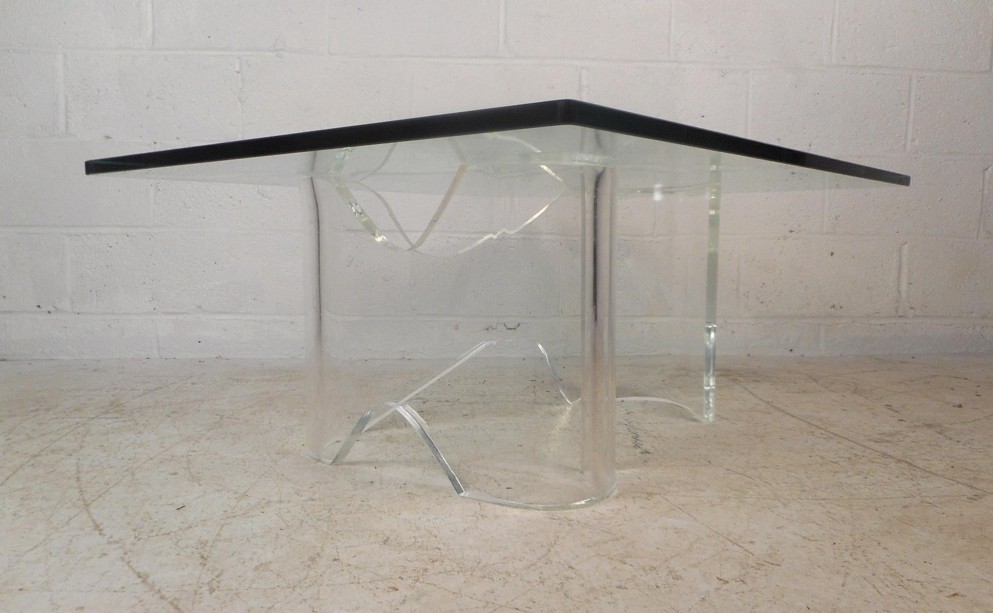 This stunning vintage modern coffee table features an unusually shaped Lucite base and a thick rectangular glass top. The unique curves of the Lucite offer sturdiness without sacrificing style in any modern interior. This fabulous midcentury