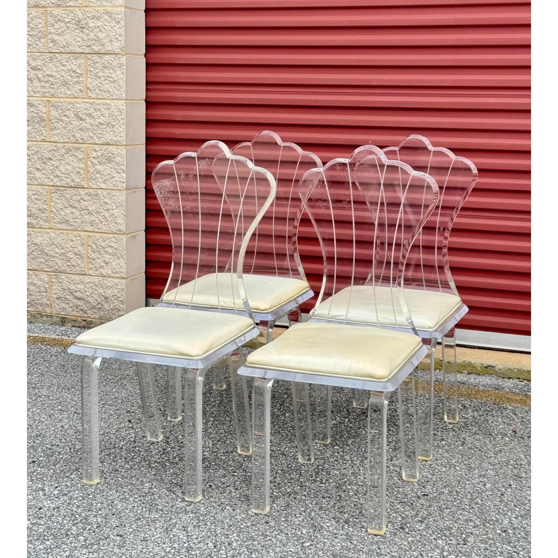 Set di quattro sedie da pranzo in lucite degli anni '70-'80 del Mid-Century Modern. Le sedie hanno una struttura in acrilico trasparente con schienali curvi e cuscini imbottiti. Il design è influenzato dallo stile Hollywood Regency e riflette l'uso