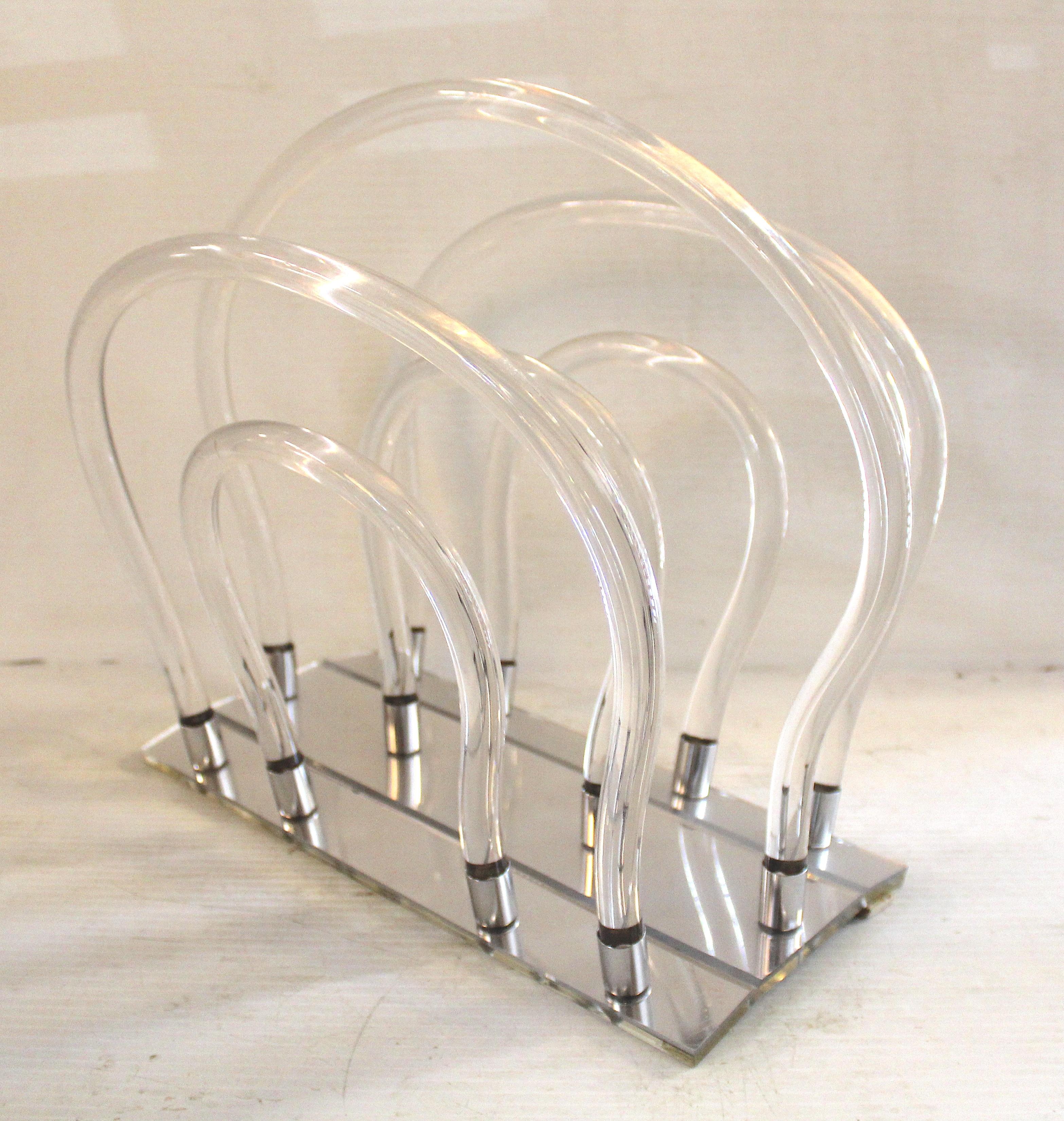 Portariviste chic di metà secolo moderno realizzato in lucite trasparente, con un design elegante e minimalista. La sua forma trasparente e le sue linee scultoree la rendono funzionale e decorativa, perfetta per aggiungere un tocco di moderna