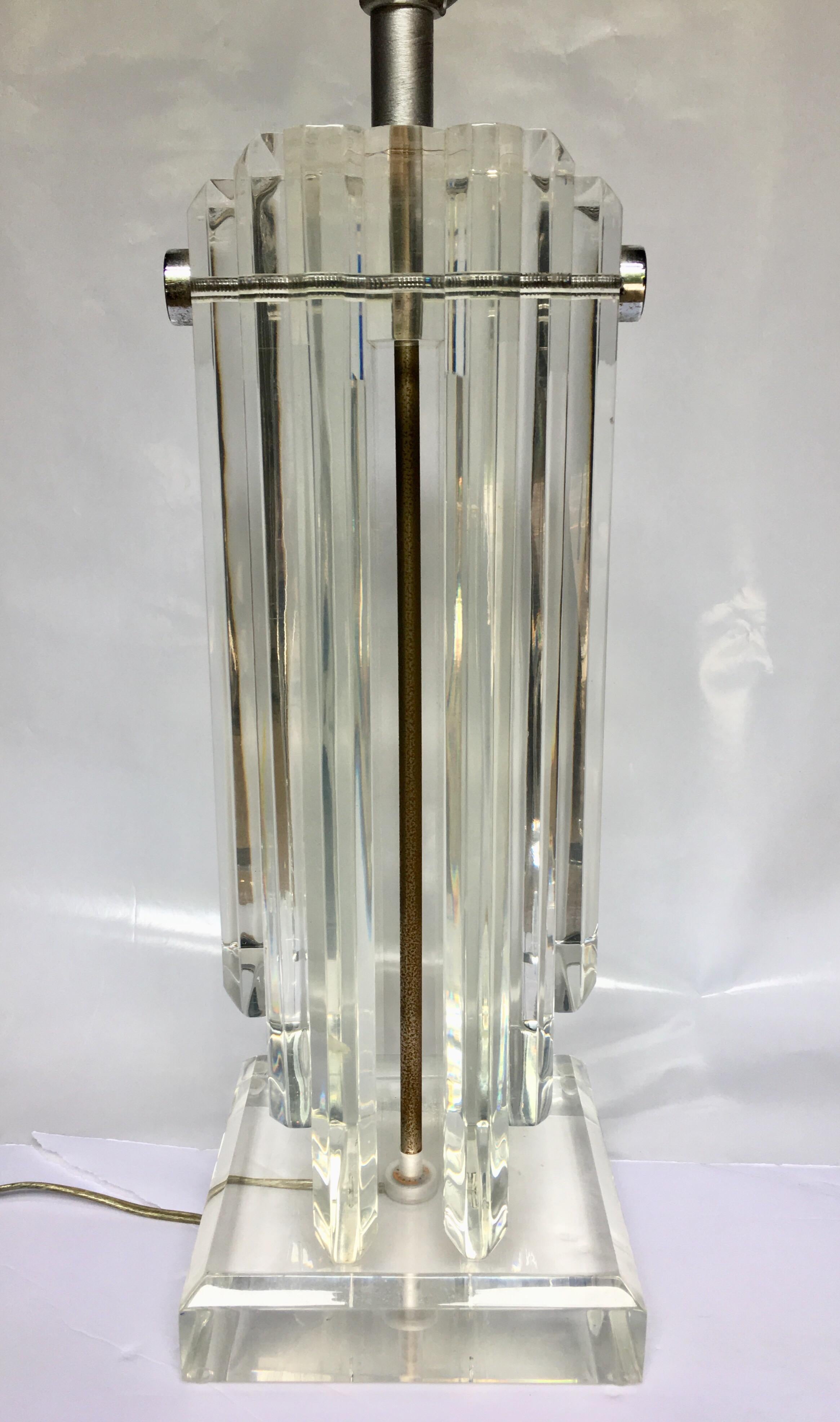 Large Hollywood Regency style Lucite table lamp featuring thick heavy stacked clear Lucite panels held together with tubular chrome rods. Lucite finial and harp included. Lamp shade not included. 

30 inches high to harp.
22.5 inches high to socket.