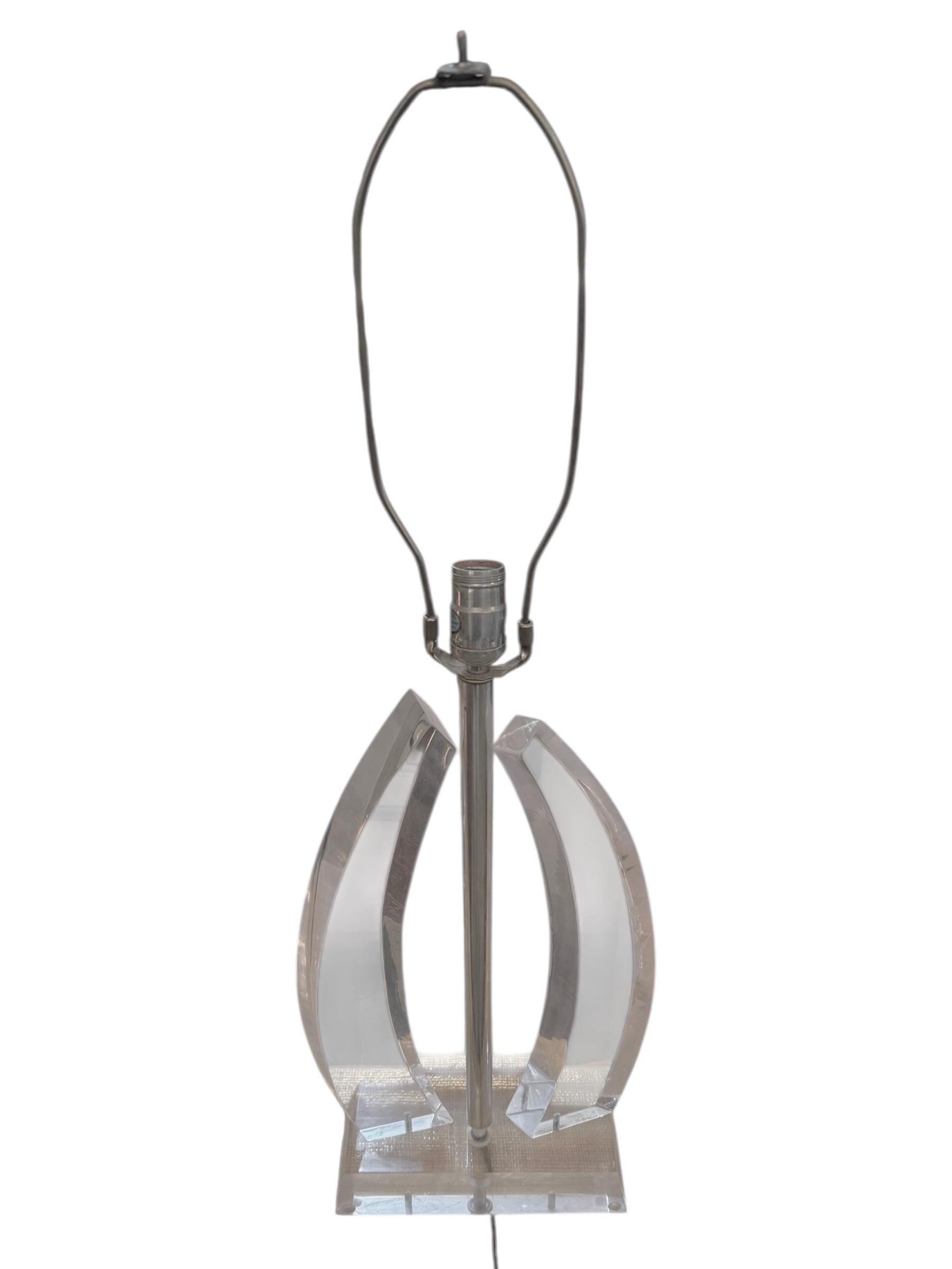 Sleek, sculptural, and unmistakably chic, this Mid-Century Modern Lucite table lamp captures the essence of retro-futuristic design. Featuring a bold, open-frame base formed by gracefully curved Lucite panels anchored by a polished central rod, this