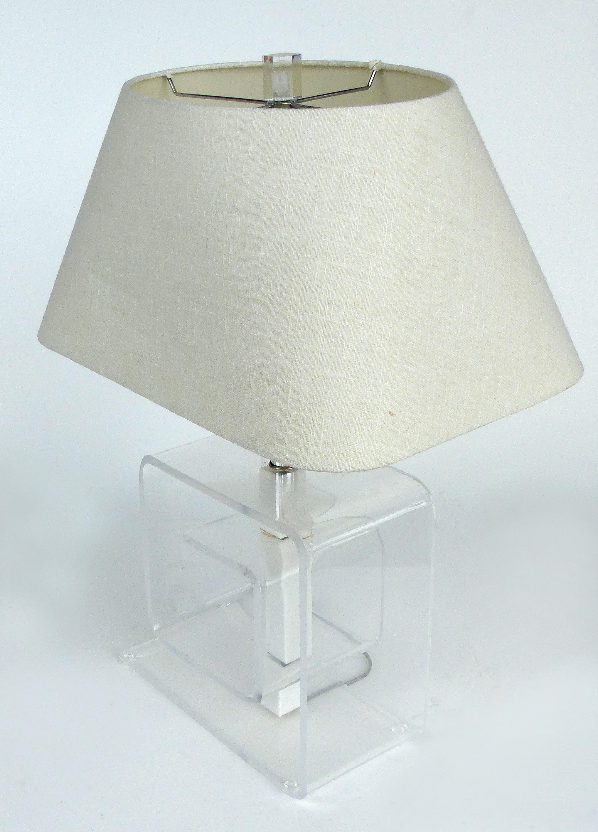 Offered for sale is a pair of Mid-Century Modern bent Lucite table lamps with acrylic columns. The lamps have chrome fitting and include the original vintage linen shades. The lamps are topped with Lucite finials. Wired and in working condition.