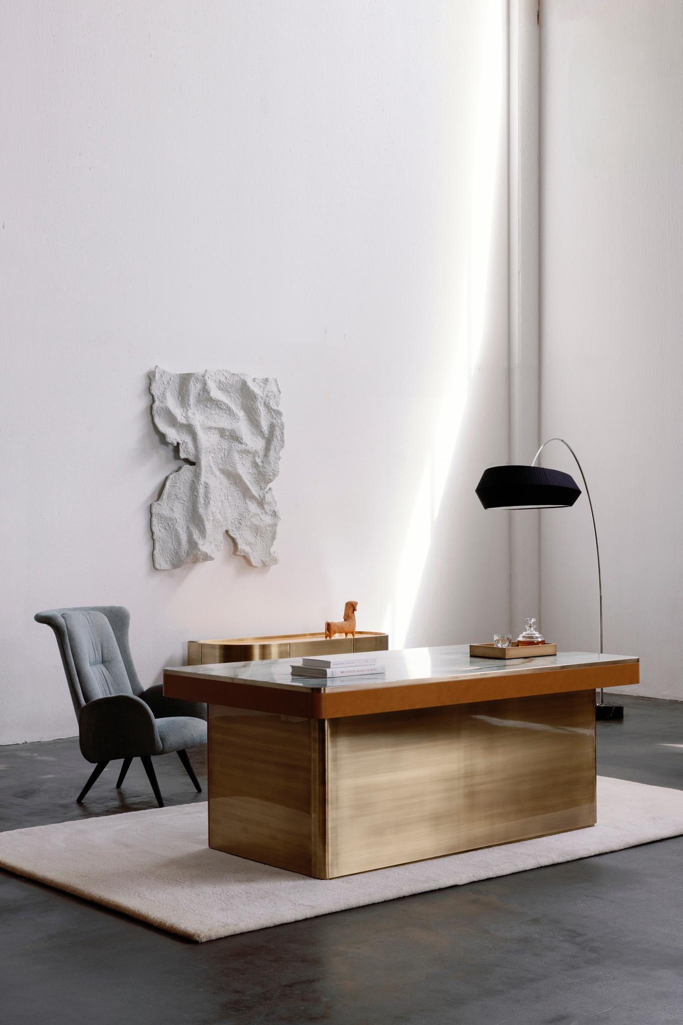 Scrivania Lugano, collezione Contemporary, realizzata a mano in Portogallo - Europa da Greenapple.

La scrivania Lugano presenta un piano di forma rettangolare, realizzato in marmo Ice Jade lucido, con dettagli in ottone antico brunito spazzolato e