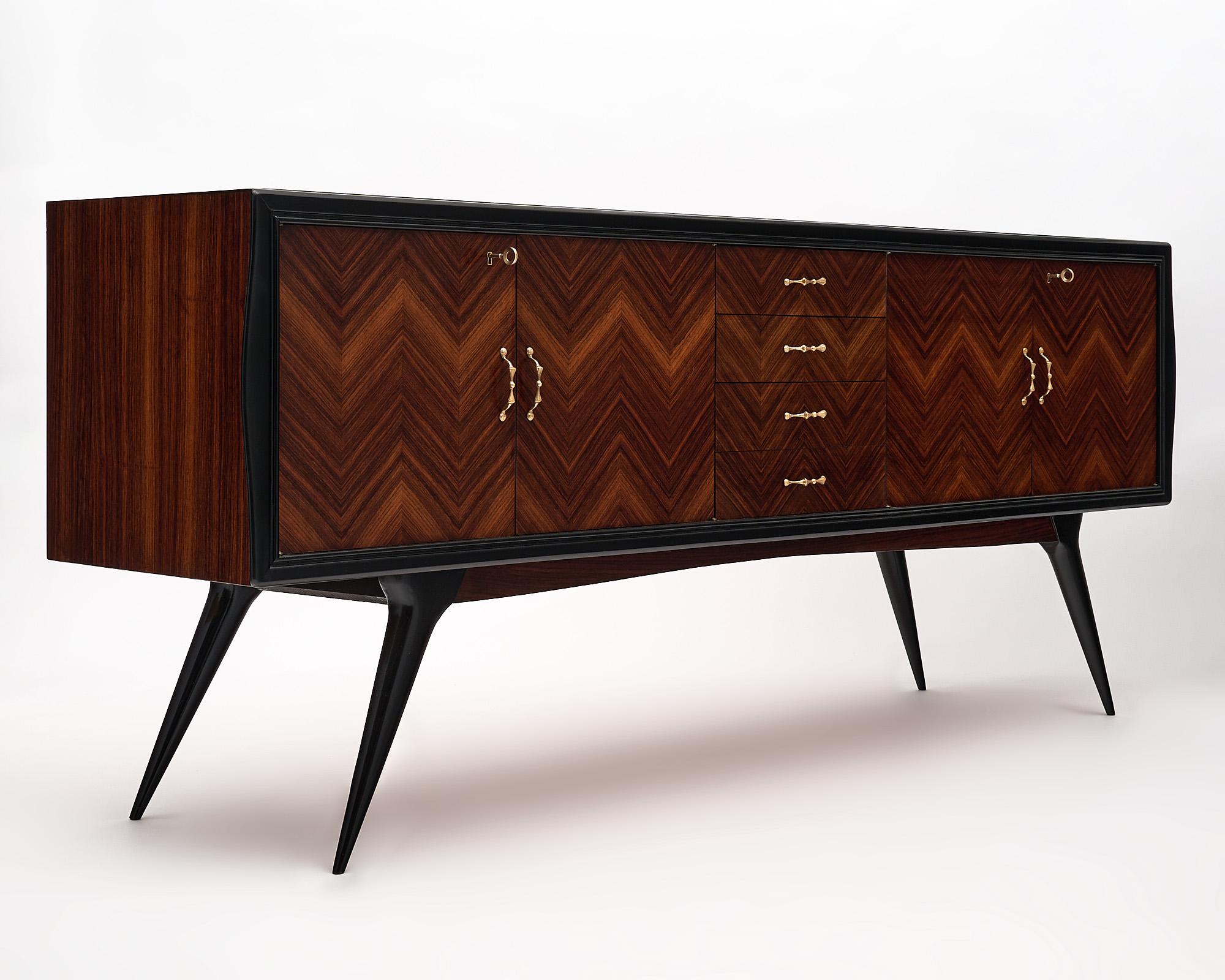 Buffet/Enfilade, French, Mid-Century Modern made of Macassar of Ebony in a chevron pattern, ebonized trims and legs. This spectacular credenza features four dovetailed drawers and two double doors opening to wood and glass shelving. Stylized solid