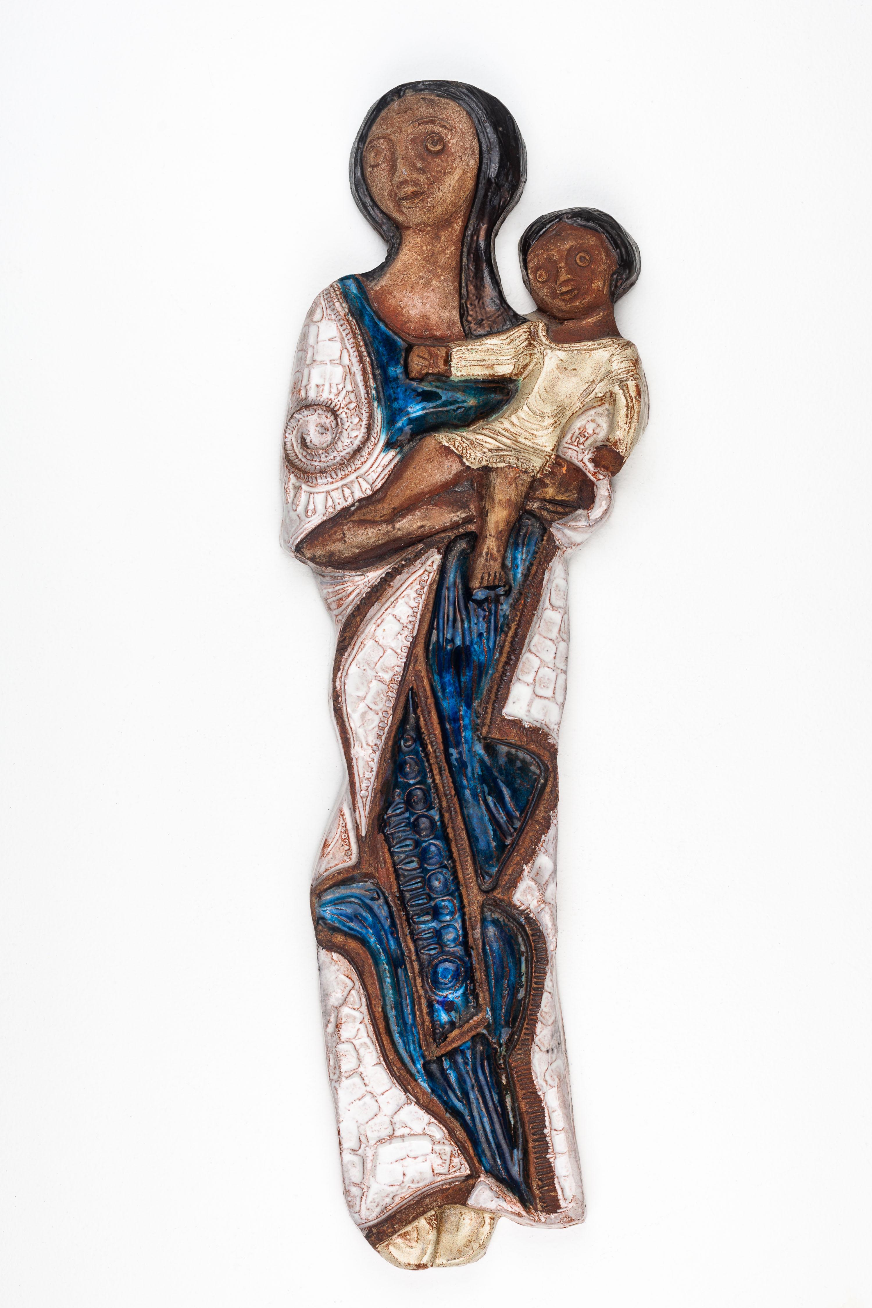 This Madonna and Child sculpture is a distinctive piece of mid-century modern ceramic art, handcrafted by a European studio pottery artist. The sculpture presents a stylized depiction of the Virgin Mary and Child Jesus, a subject deeply rooted in