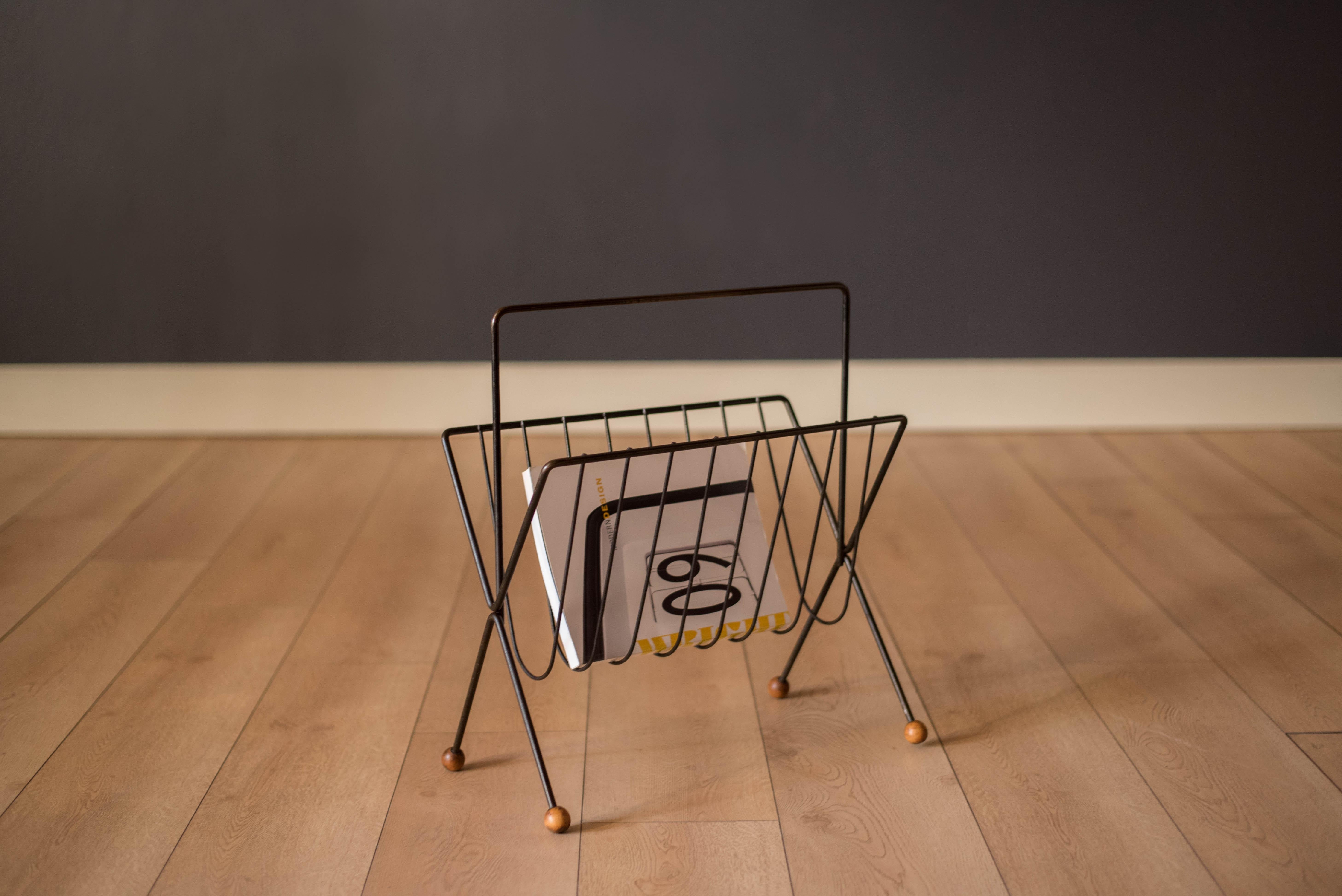 Vintage magazine rack stand designed by Tony Paul circa 1950's. This unique home decor piece is made of bent iron and is accessorized with protective wooden ball feet. 

Interior: 17.5
