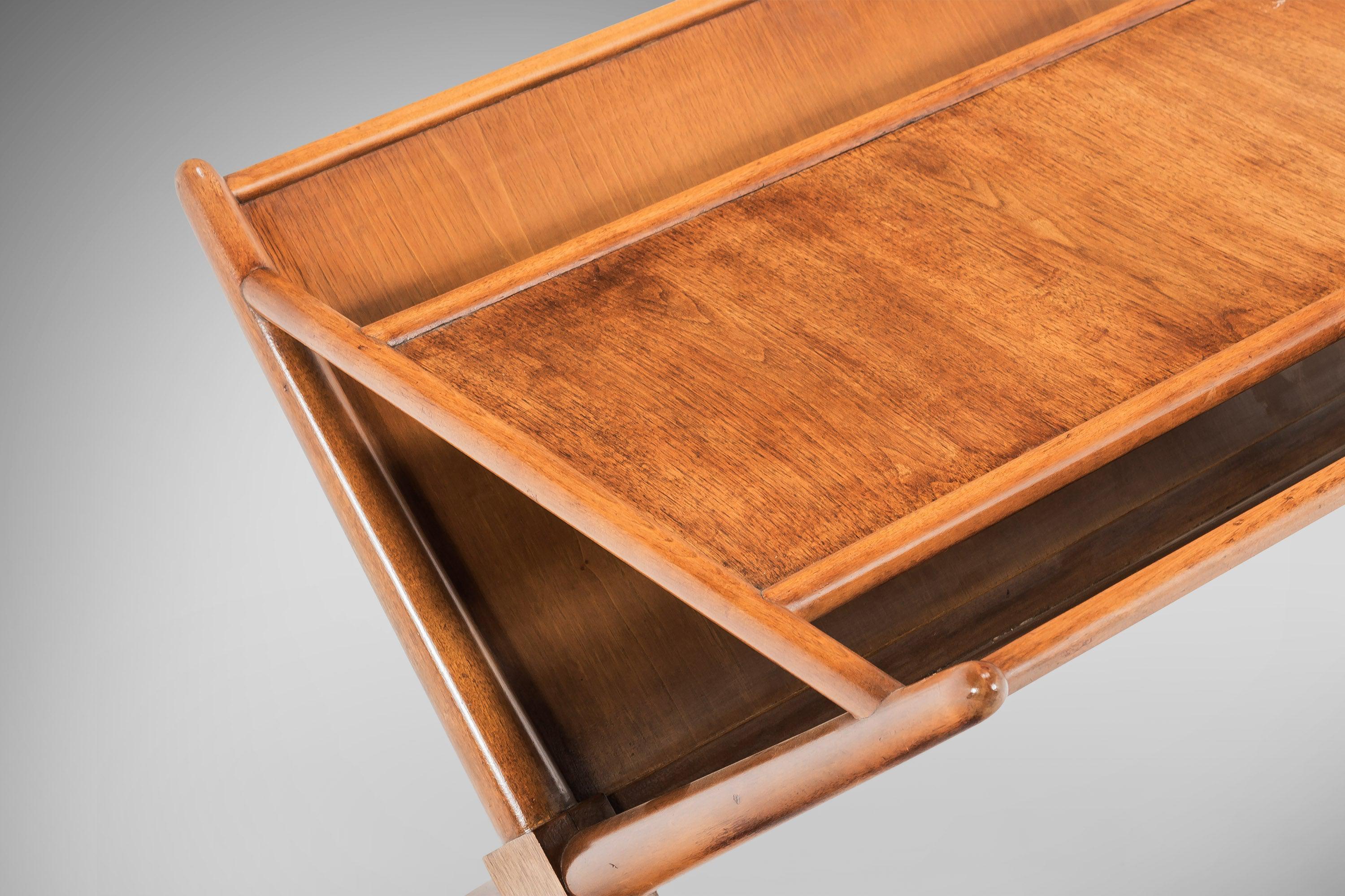 Versatile magazine table designed by T.H. Robbsjohn Gibbings for Widdicomb Furniture. Two angled panels, made of American walnut, allow for magazines and newspapers to be stored on sides with an ample top surface for a lamp. Equal parts functional