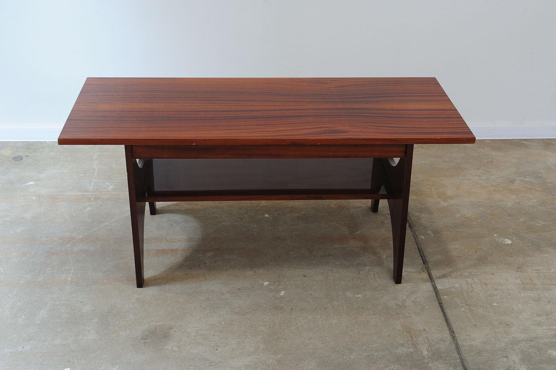 This mid century modern coffee table was made in the former Soviet Union in the 1970´s as a part of a mahagony mid century living room.
Its design is elegant and modern.

It has interestingly shaped legs with arched cutouts and a distinctive