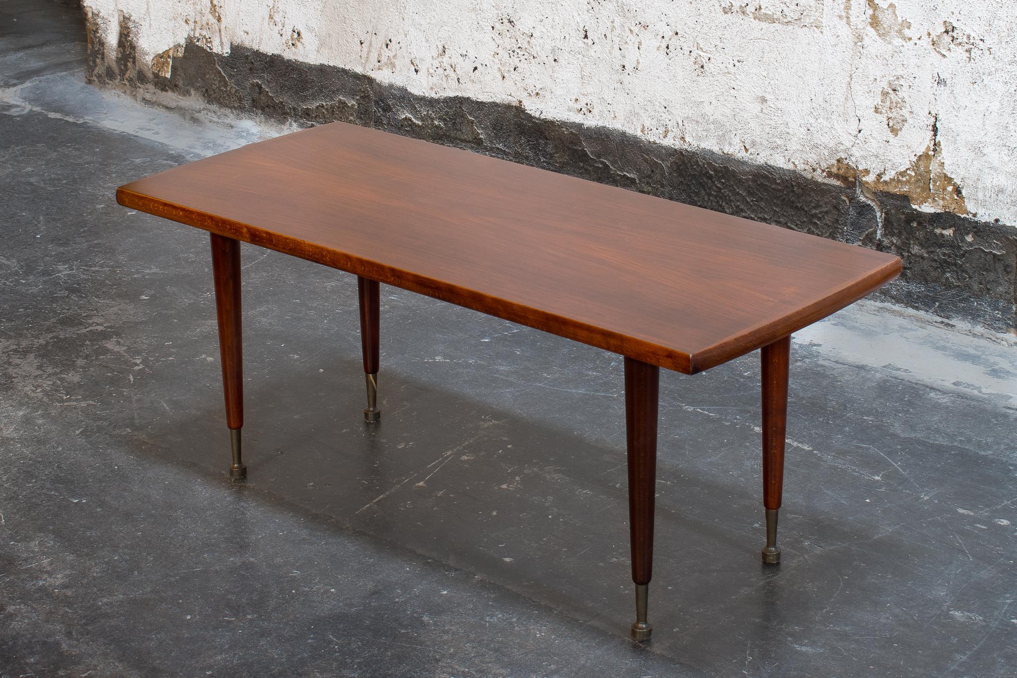MCM Mahogany coffee table with turned legs and brass caps on the feet. The tabletop is in phenomenal condition and is a beautiful dark, rich, mahogany.
