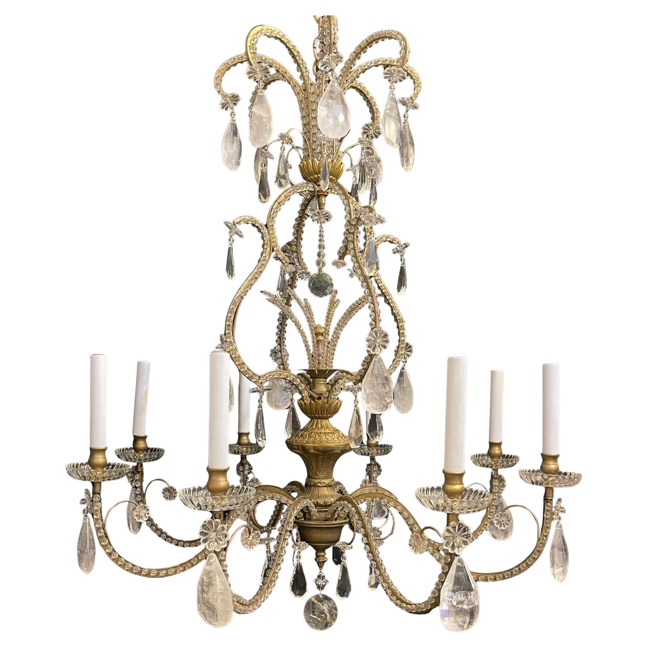 Un meraviglioso lampadario di grandi dimensioni in stile Maison Baguès in oro dorato con gabbia per uccelli e bouquet centrale con cristalli alternati e cristalli di rocca sospesi da fiori di vetro artistico. Questo lampadario ha 8 prese a