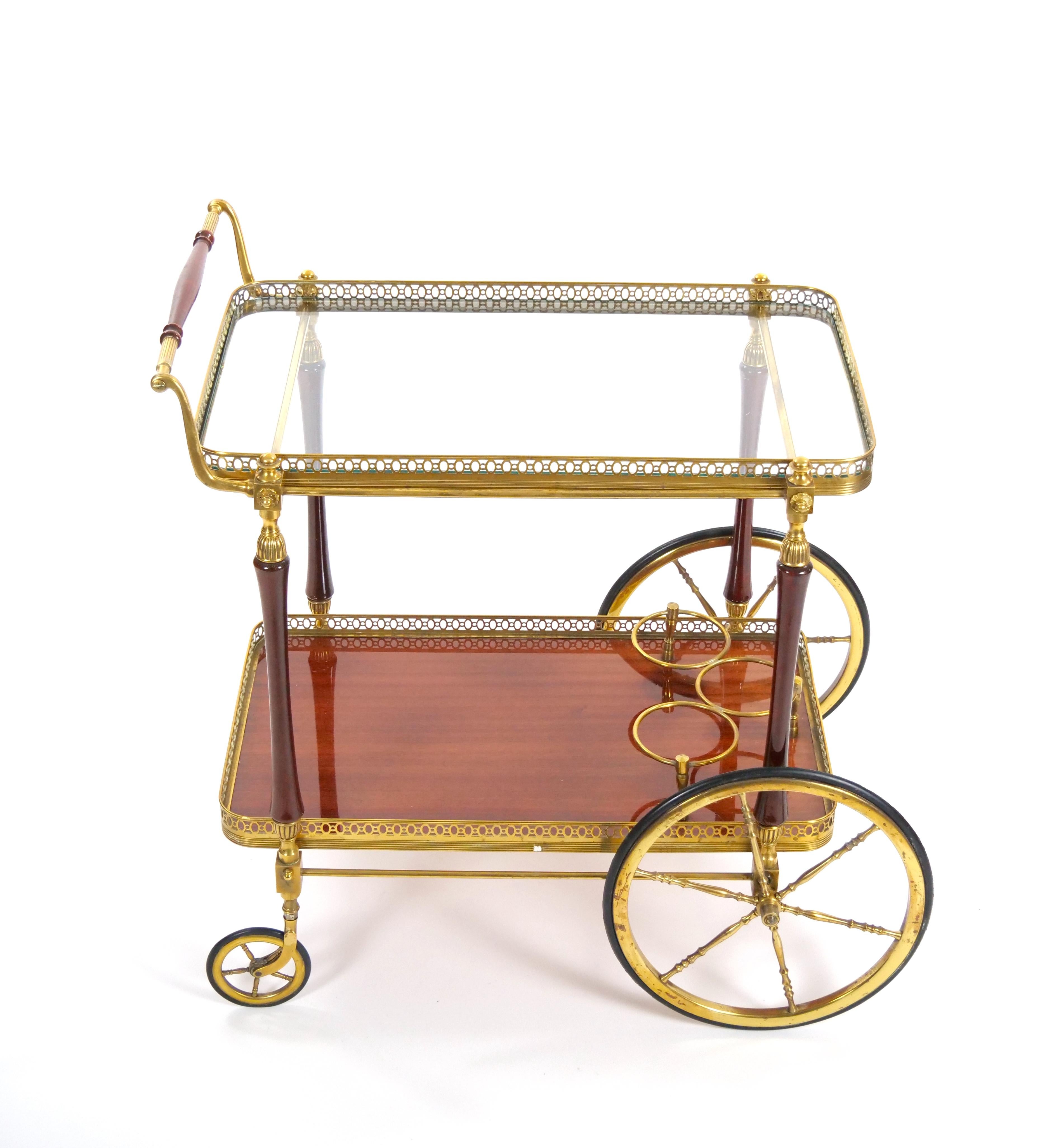 This elegant neoclassical style bar cart, crafted in the 1950s by the renowned French designer Maison Jansen, embodies sophistication and functionality. The cart features a refined combination of brass, glass, and mahogany, creating a chic and