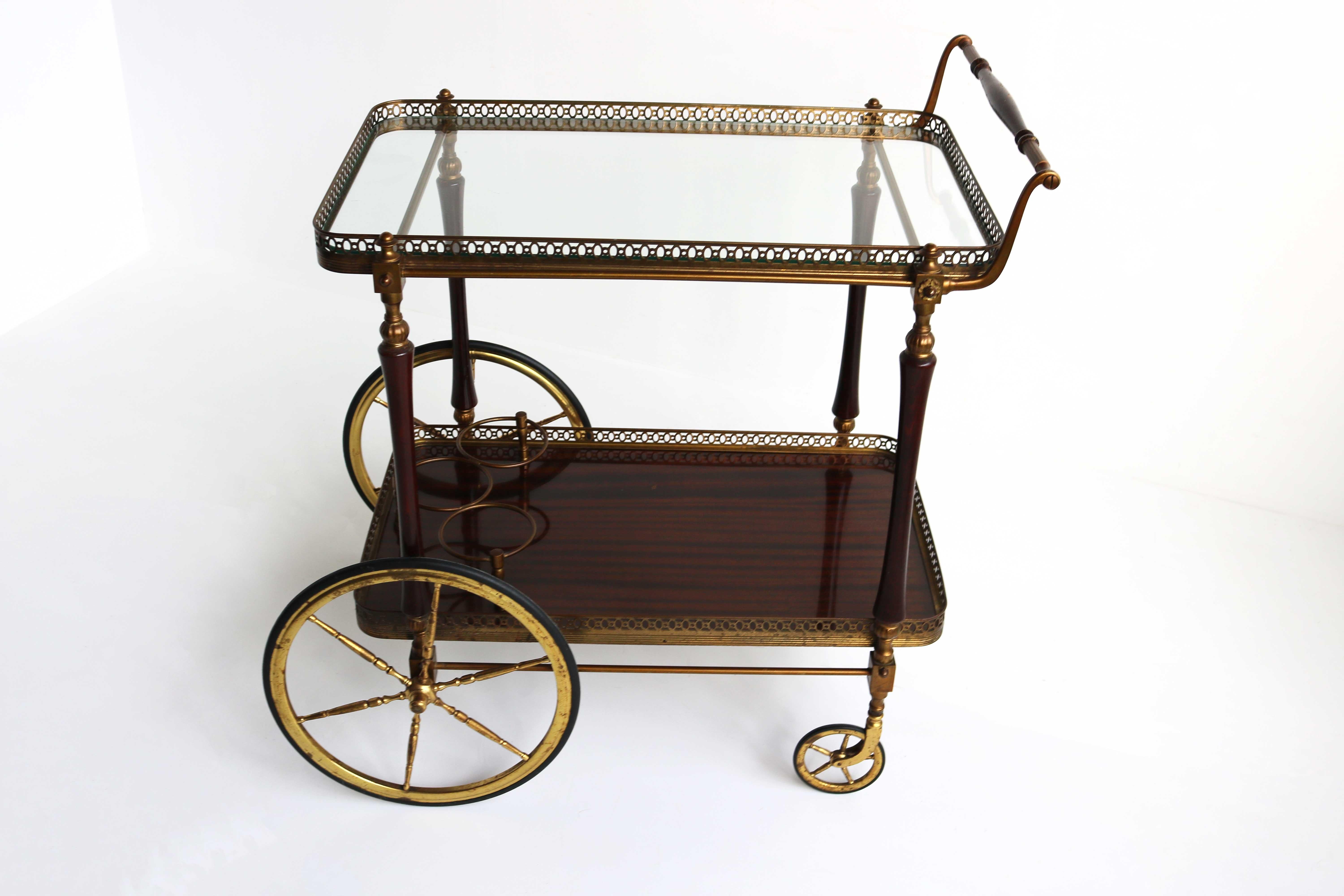 This very elegant neoclassical style bar cart is made of brass , glass and mahogany . 
This is a work by famous French designer Maison Jansen, circa 1950.
Great for displaying your bar set, or a wonderful item to roll out with your pastries and