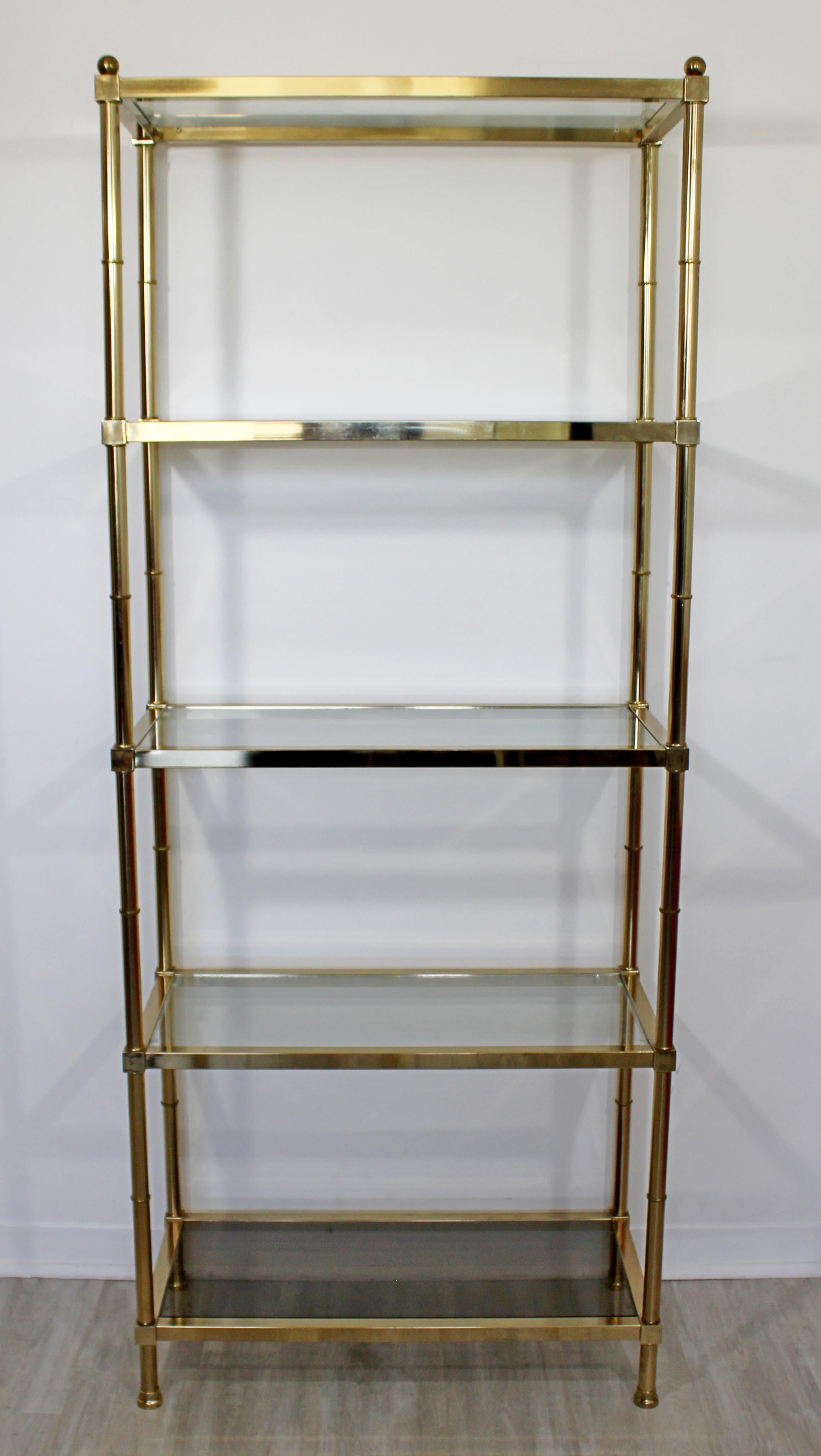 For your consideration is a stunning, brass and glass shelving unit étagère, with five shelves and the bottom shelf is smoked, by Maison Jansen, circa 1960s. In excellent vintage condition. The dimensions are 30.5