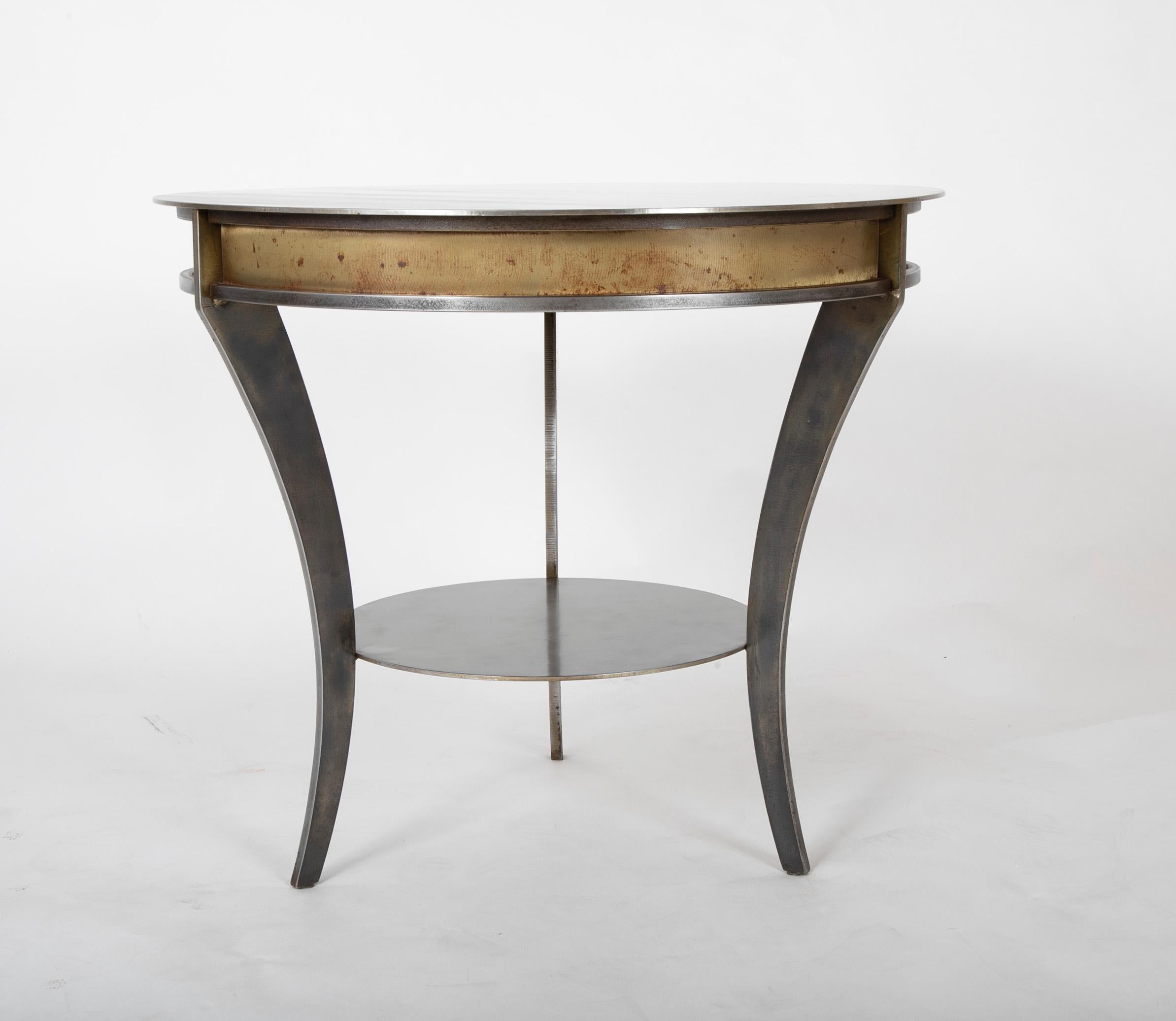 Maison Jansen style round steel side table on tripod legs with a patinated pale gold band. A modern take on the neoclassical style, the simple lines and modern form speak elegance.