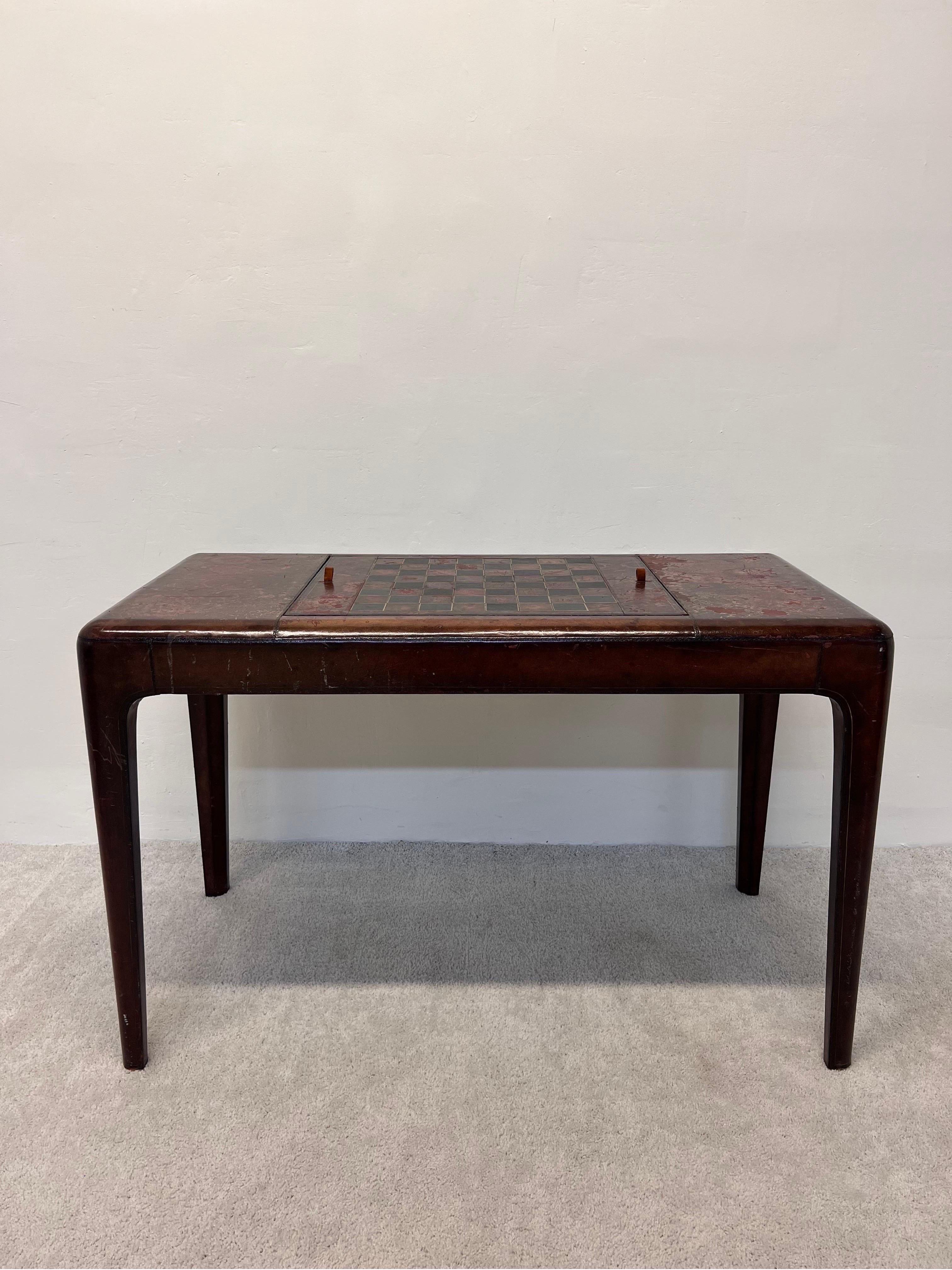 Maitland-Smith distressed leather game table with both chess/checkers and Backgammon reversible board. Leather wrapped table has two side drawers on the side for game pieces and card storage. Game pieces not included. Opening height for chairs: