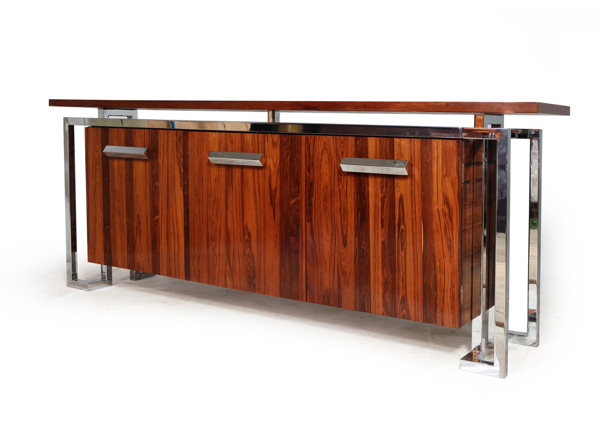 MANDARIN SIDEBOARD BY PIEFF
A mid century rosewood and chrome sideboard from the high end Mandarin range it has tree doors with glass adjustable height shelves and two internal drawers above chromed sure steel supports the sideboard has been part