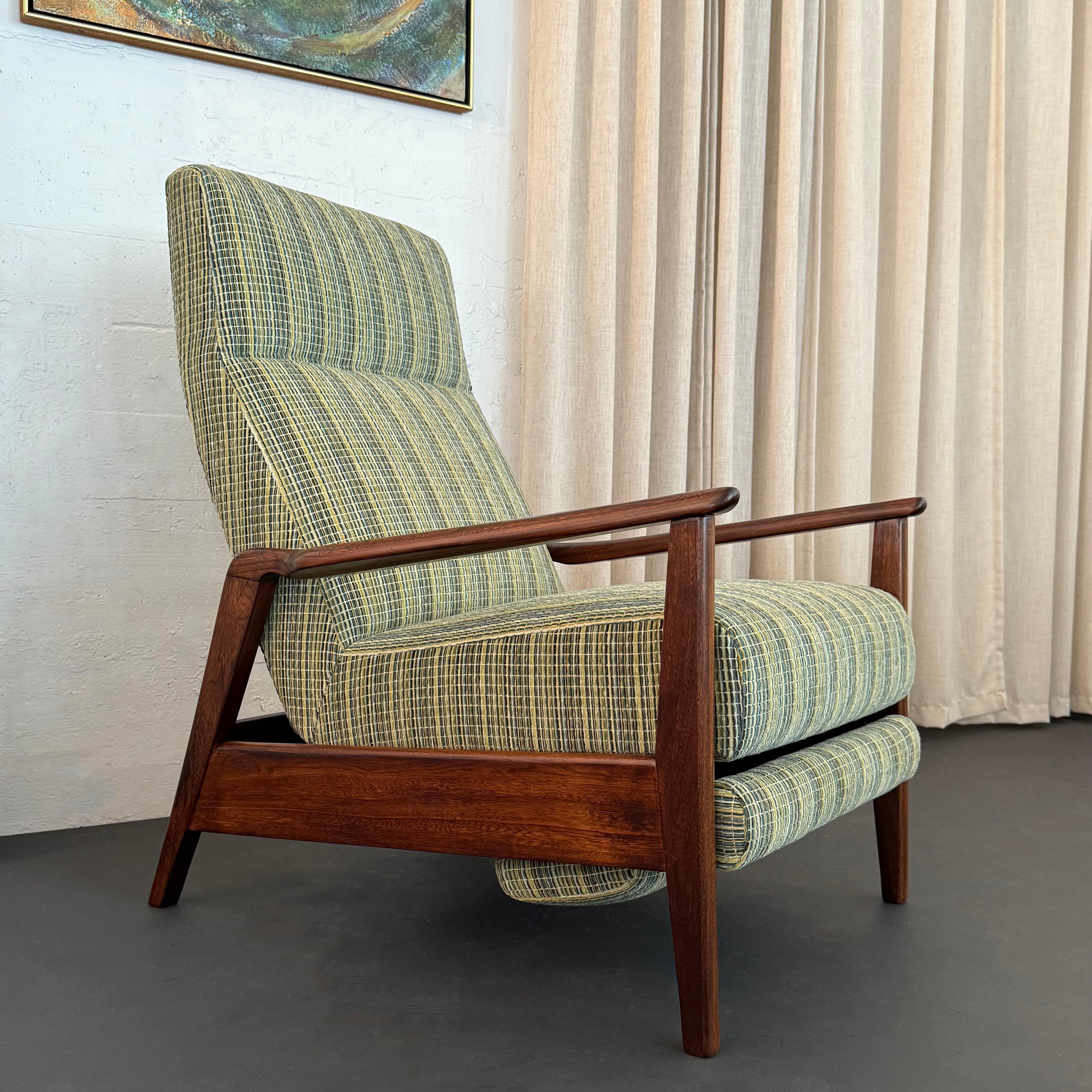 This stylish American Mid-Century Modern recliner lounge chair with retractable footrest was produced by Home Chair Co. of Ronda, North Carolina circa the 1960s. The recliner has a high segmented back and seat that is supported by a stylish and